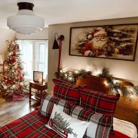 Cozy winter bedroom decorated with red plaid bedding, Christmas pillows, a garland-covered wooden headboard, and a festive Christmas tree.