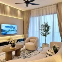 Cozy modern living room with beige seating, wood slat walls, sheer curtains, warm lighting, and a large indoor tree.