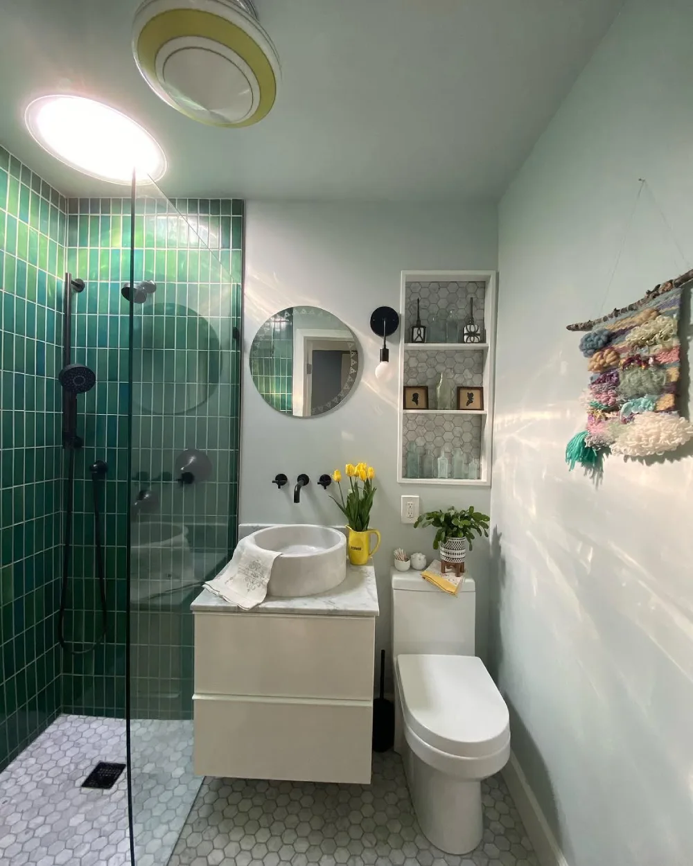small bathroom with deep green vertical shower tiles, white walls, recessed shelves, and a compact vanity