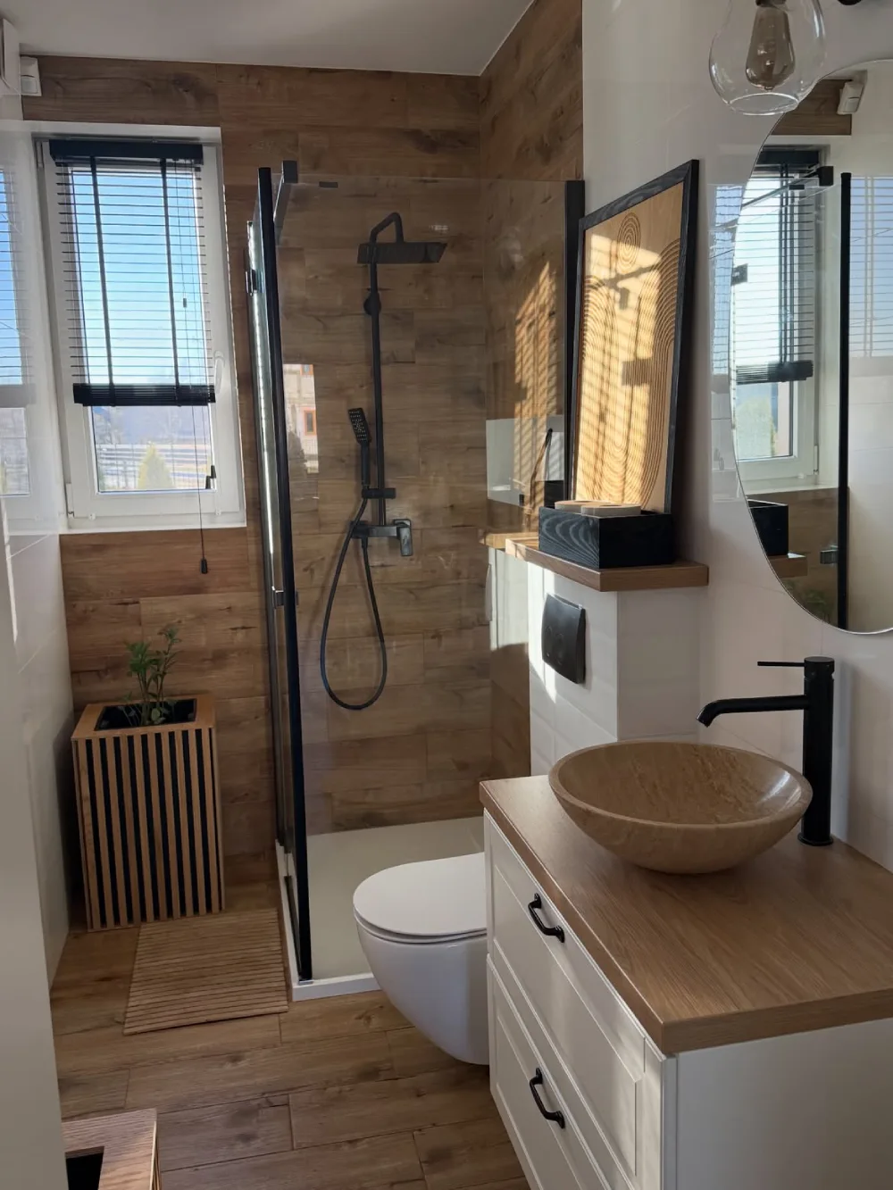 narrow bathroom with wood-look tiles, black shower fixtures, glass enclosure, and a wood countertop vanity