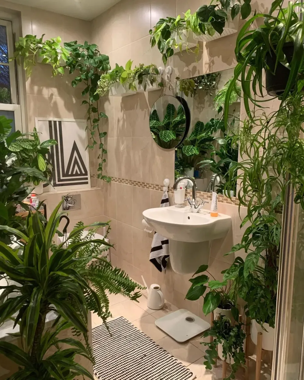 Small bathroom filled with lush tropical plants around the vanity