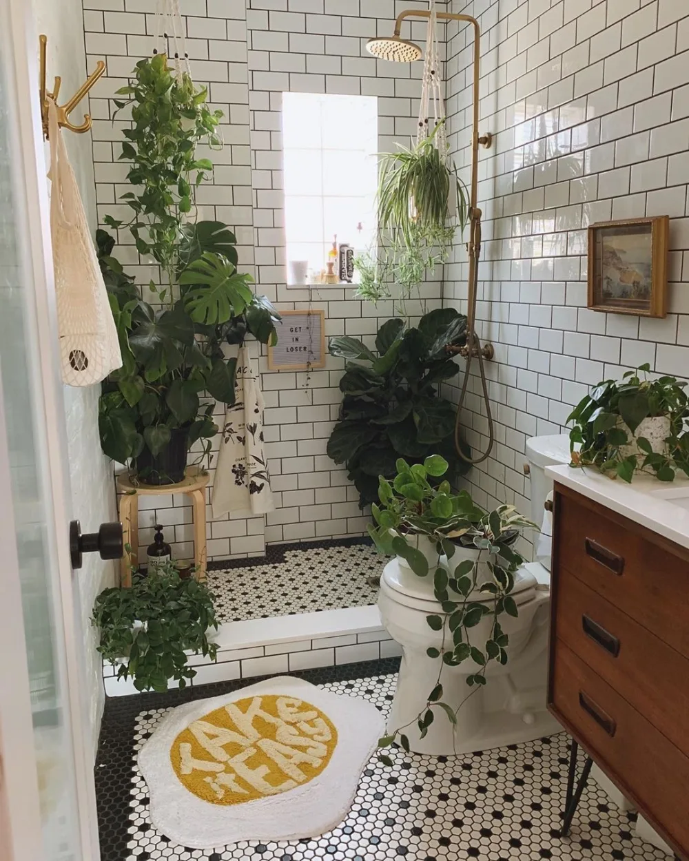 White subway tile bathroom decorated with hanging and potted plants