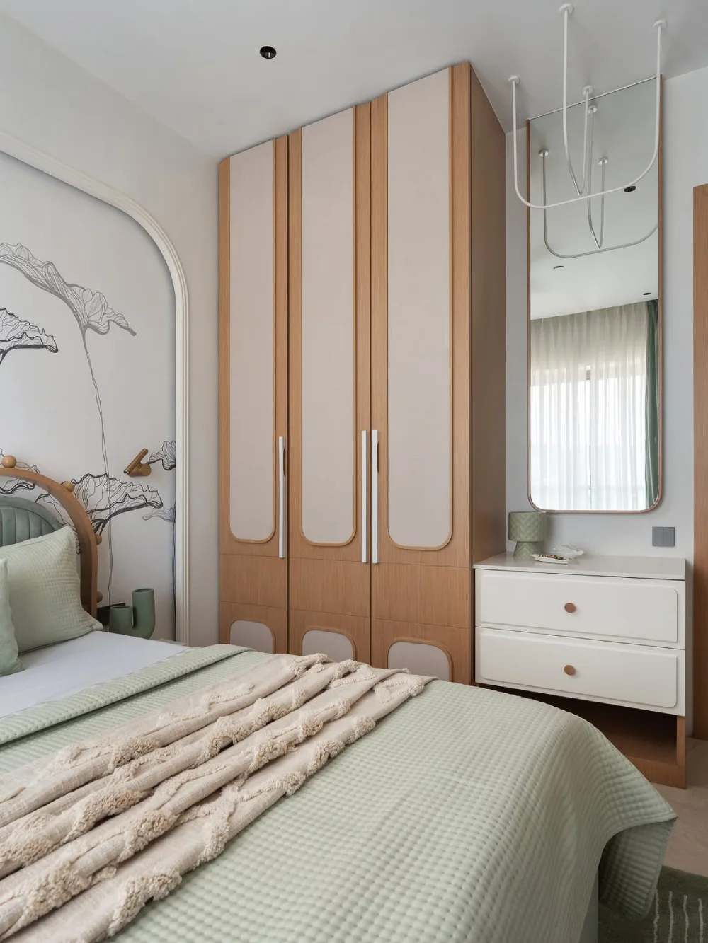 green bedroom with custom wood wardrobe, floral wall art, and soft textured bedding