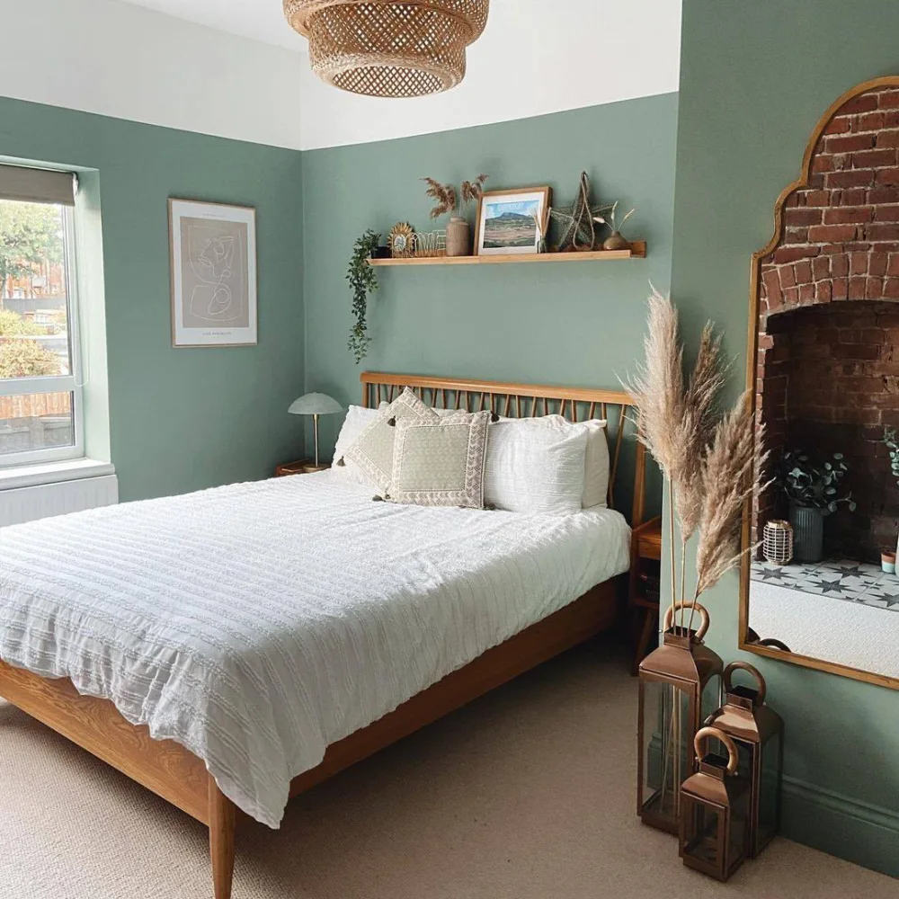 deep green bedroom with wood bed frame, white bedding, and exposed brick fireplace