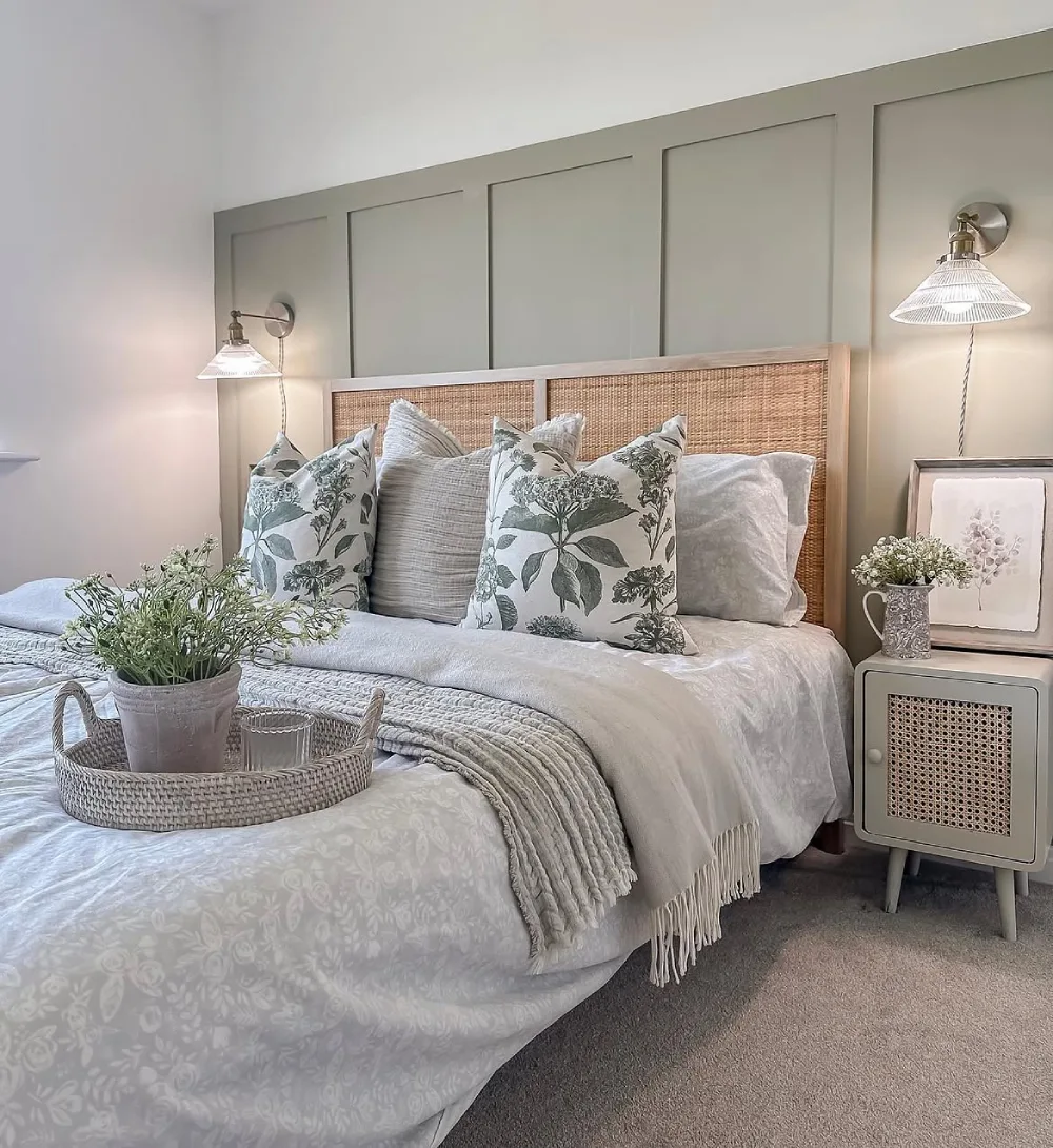 green bedroom with botanical artwork, upholstered bed, and floral pillows