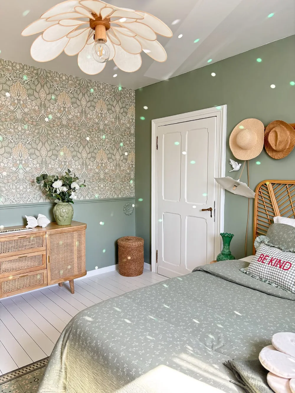 sage green bedroom with floral wallpaper, rattan furniture, and a white metal bed