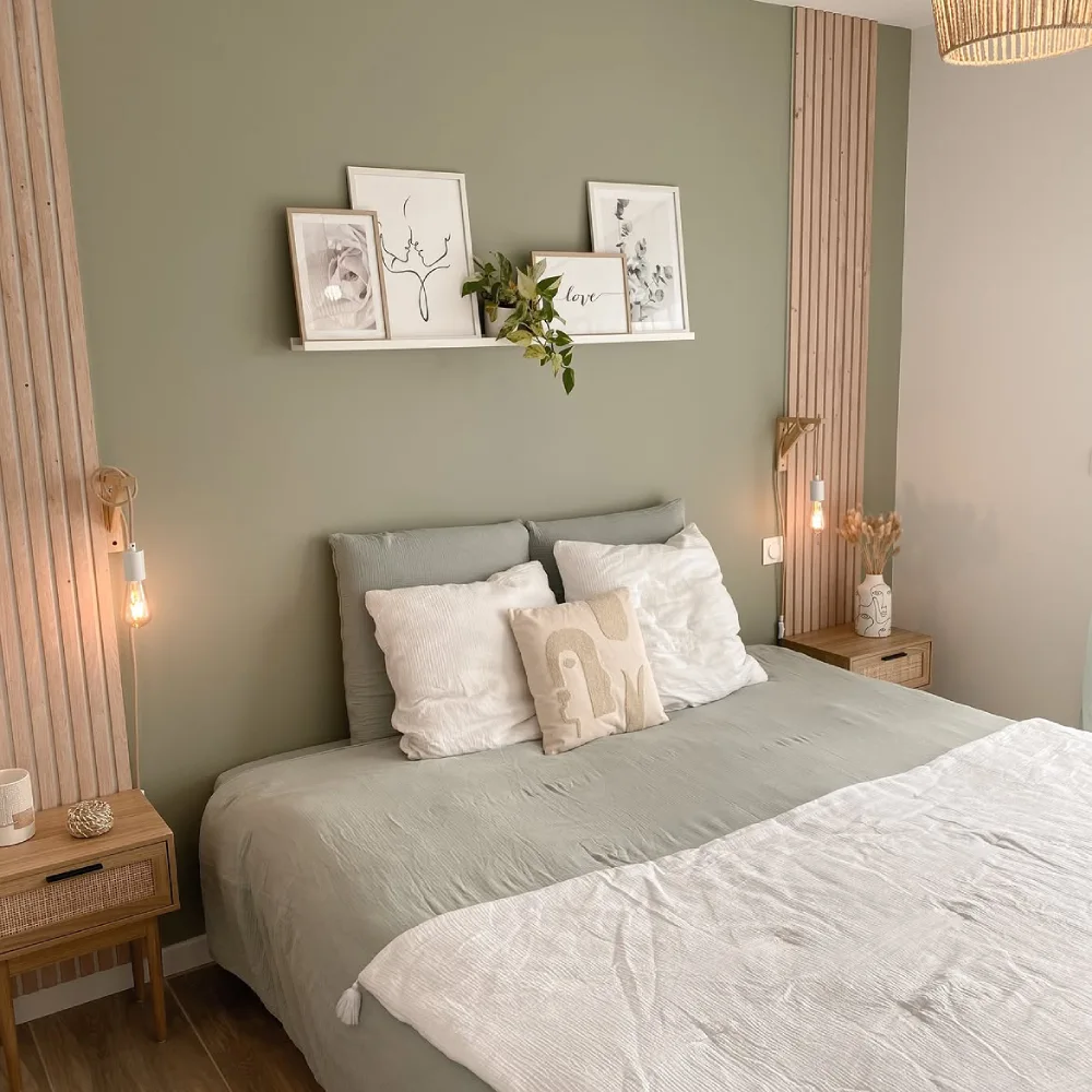simple sage green bedroom with natural wood slat accents, white bedding, and framed artwork