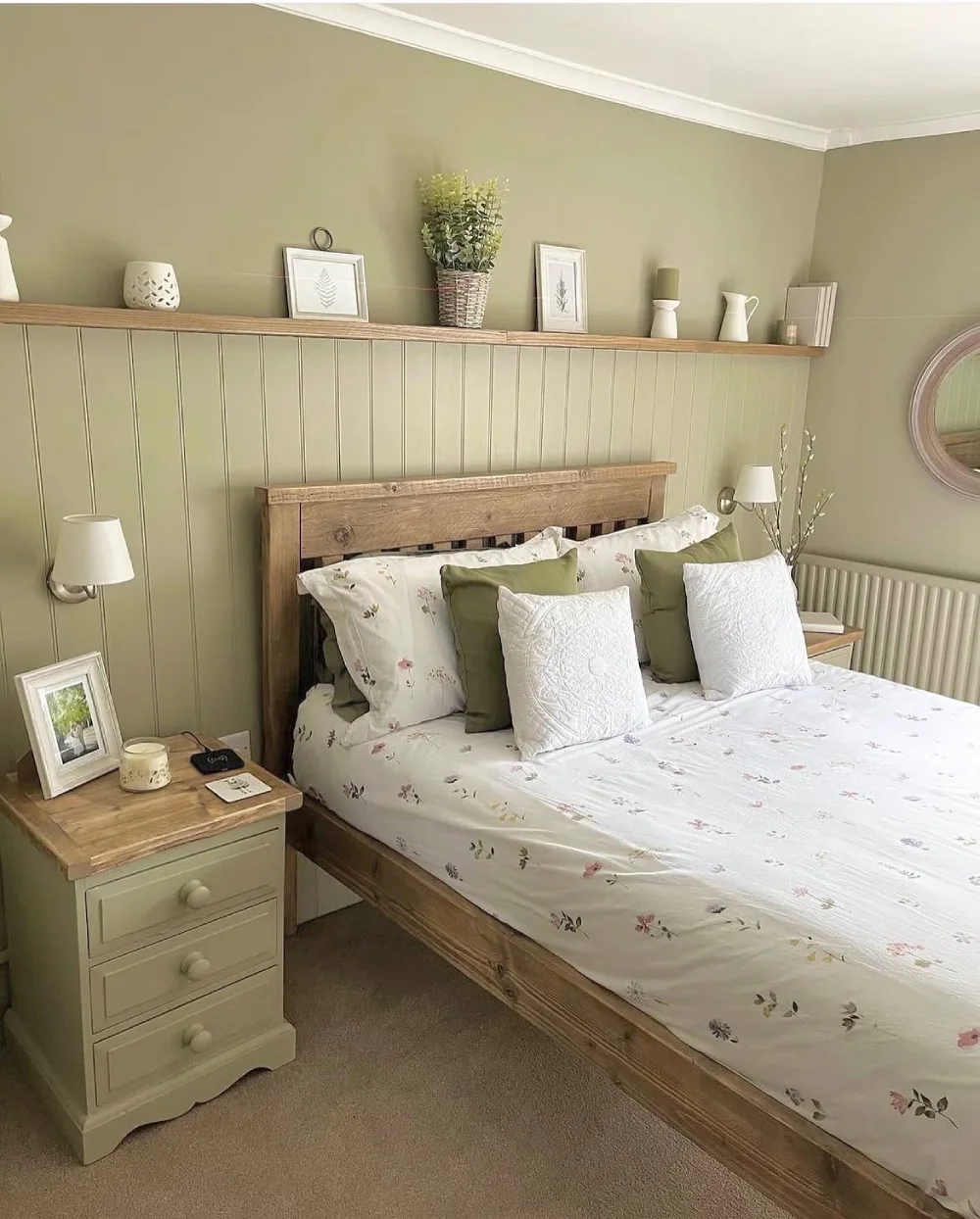 cottage bedroom with sage green paneling, floral bedding, wood furniture, and soft neutral decor