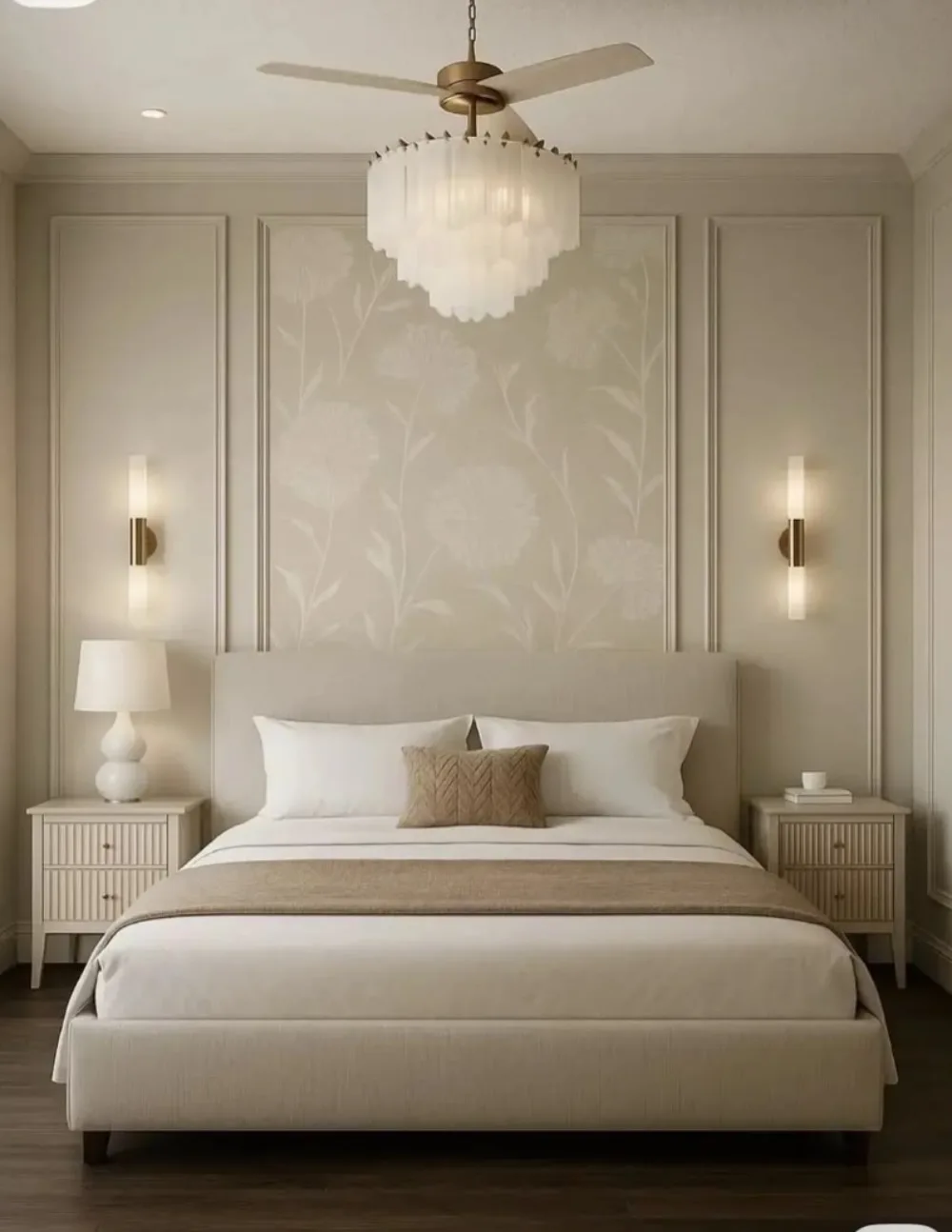 Neutral bedroom with a beige floral accent wall framed by decorative molding, a cream upholstered bed, white nightstands, and warm brass lighting
