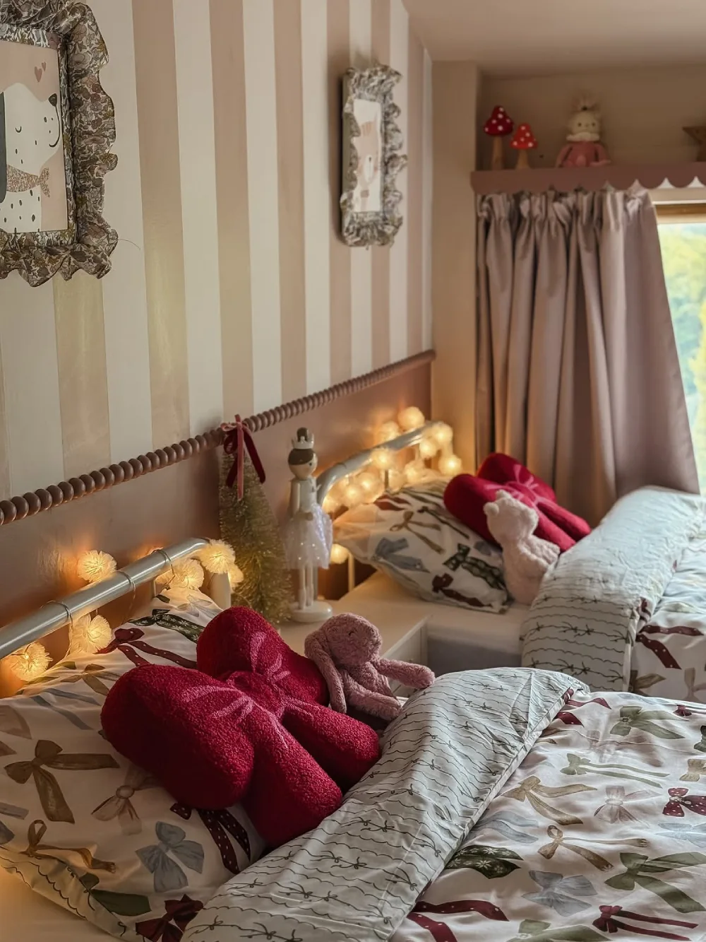 Cozy children's bedroom with festive bow-patterned bedding, plush toys, and warm lights