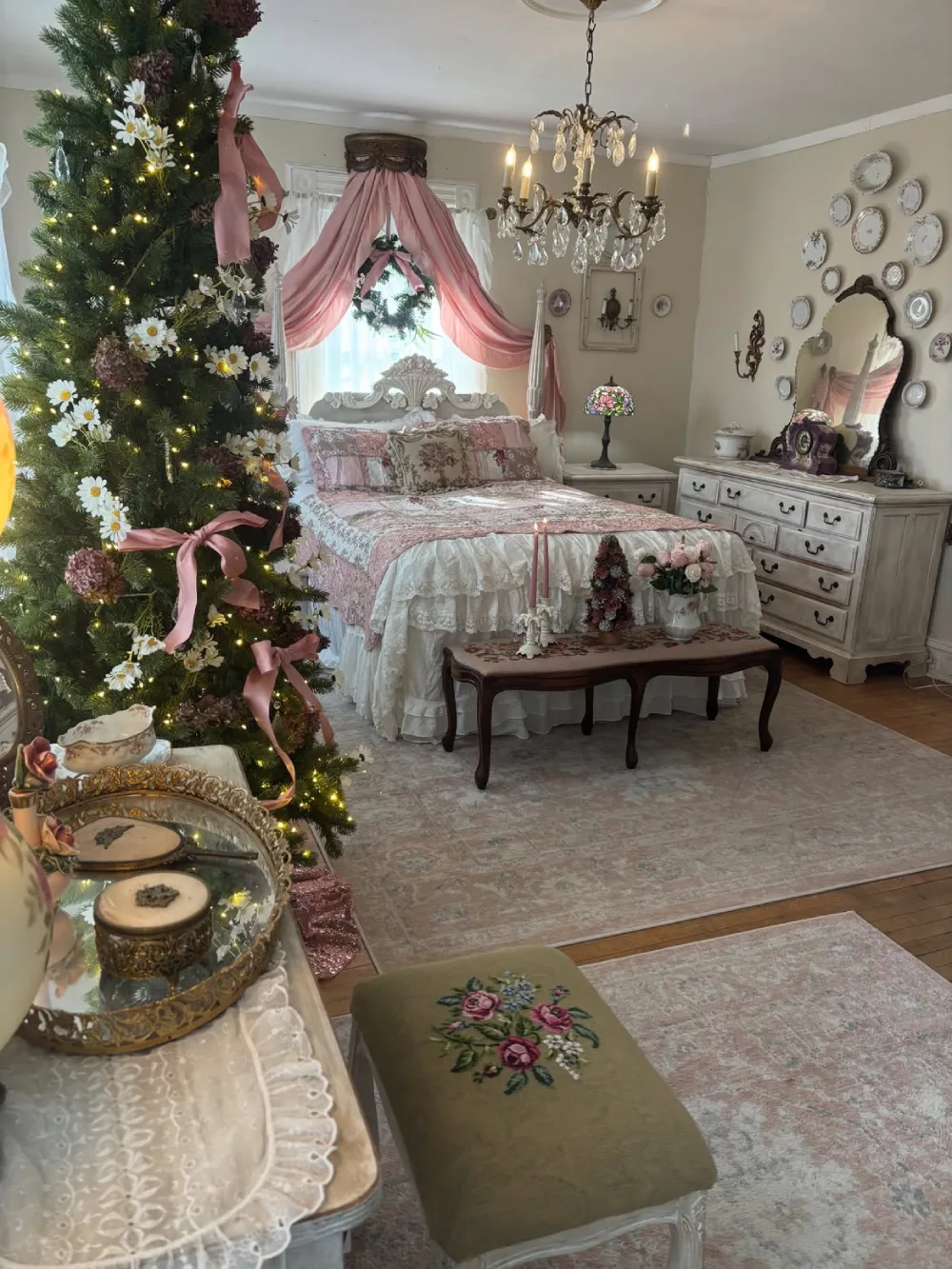 Romantic pink Christmas bedroom with floral bedding, canopy, and decorated tree