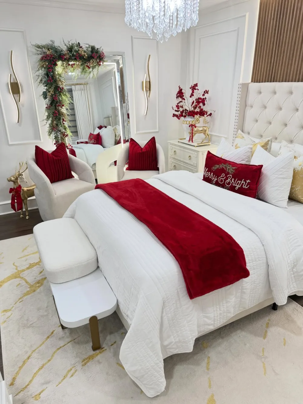 Elegant white bedroom with red Christmas pillows, a red throw, and festive greenery