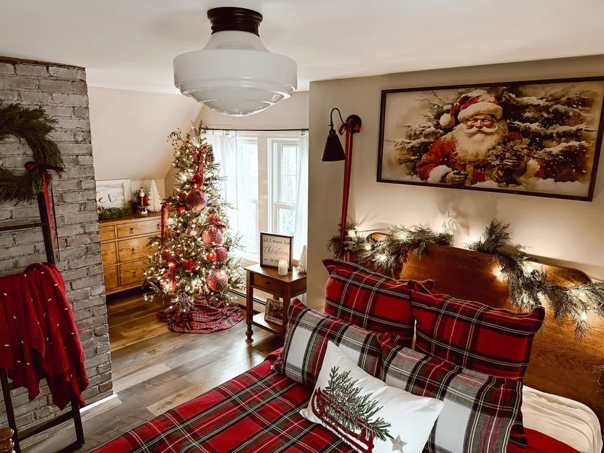 Cozy winter bedroom decorated with red plaid bedding, Christmas pillows, a garland-covered wooden headboard, and a festive Christmas tree.