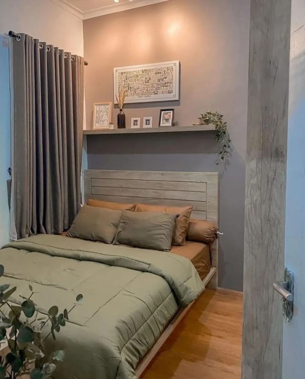 Small bedroom with a wooden bed, floating shelf above the headboard, and green bedding