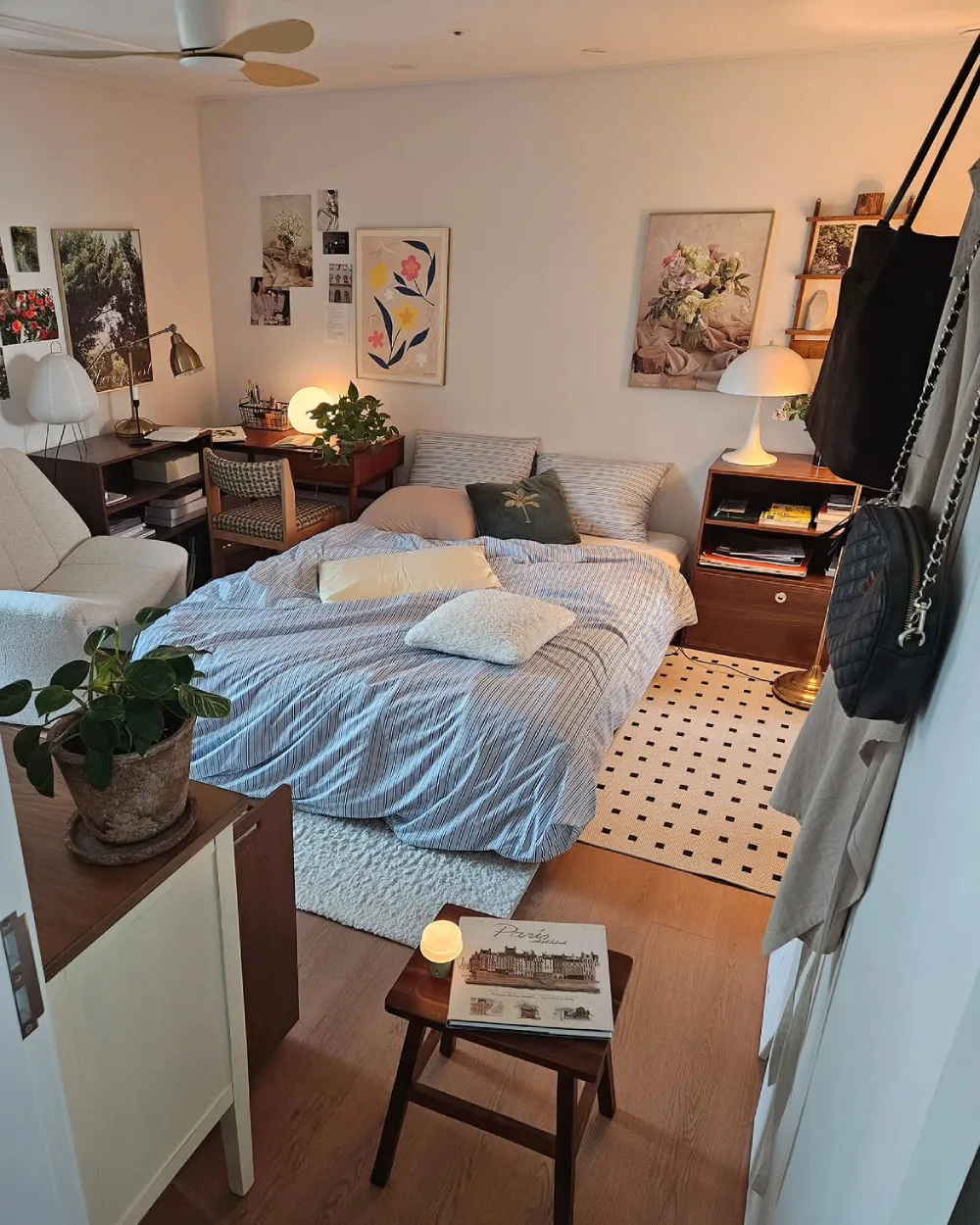 Small bedroom with a bed, compact desk, bookshelves, and layered lighting
