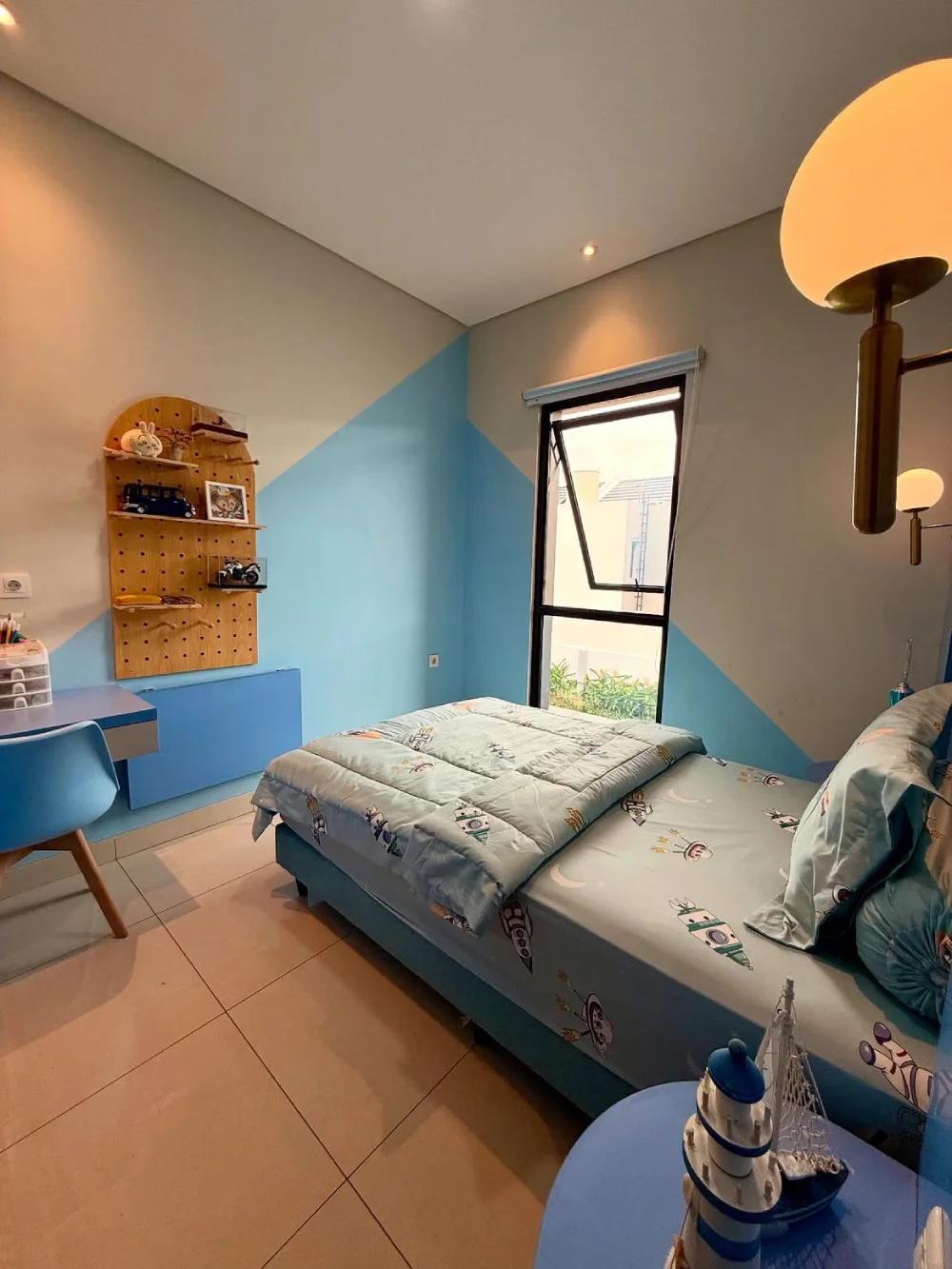 Blue kids bedroom with a compact desk, pegboard storage, and built-in furniture