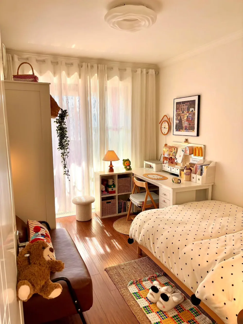 Small bedroom with a bed, compact sofa, desk, and warm wood flooring