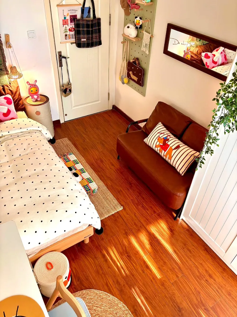 Small bedroom with a compact sofa beside the bed and wall-mounted storage
