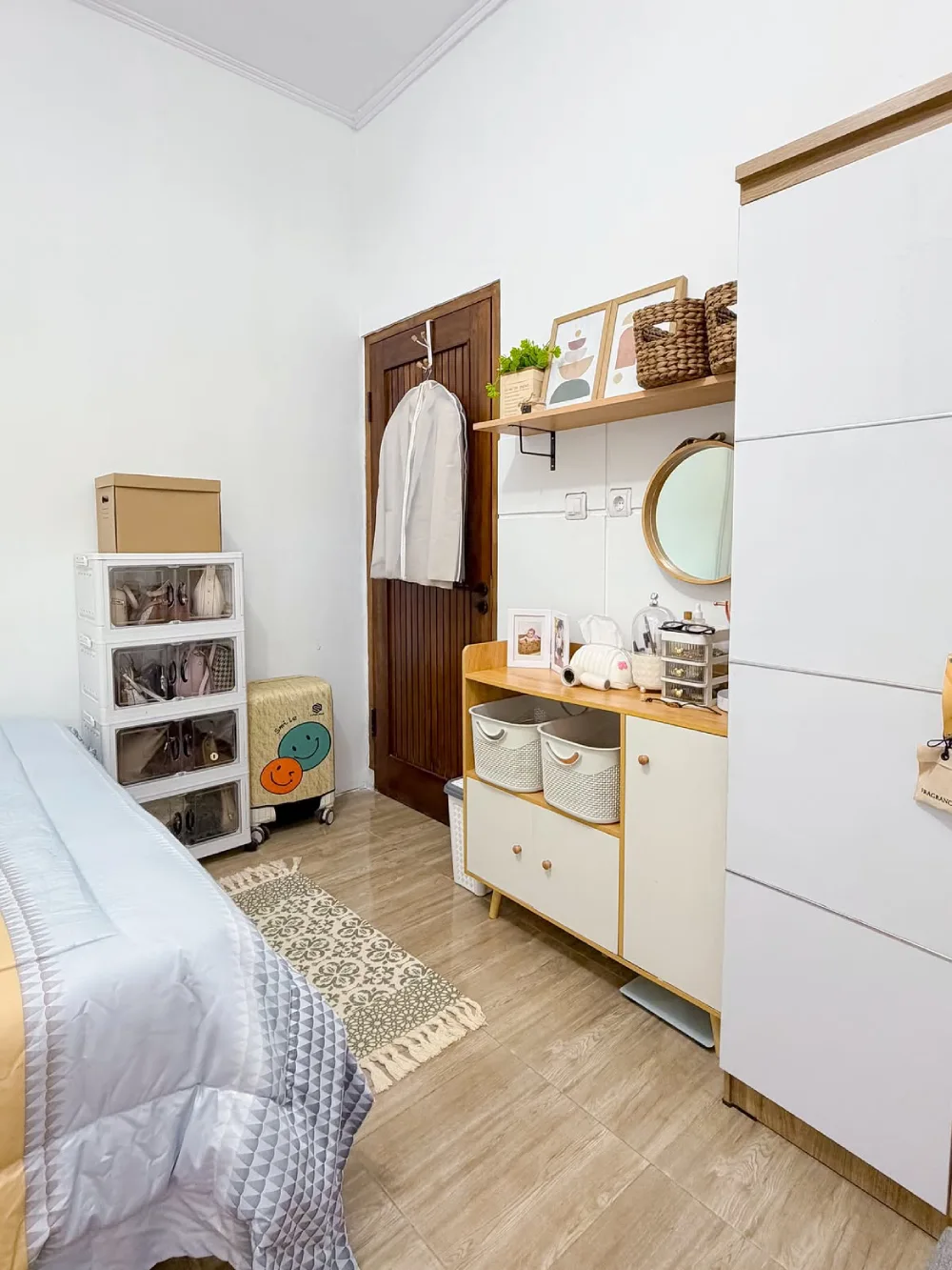 Small bedroom with compact drawers, open shelving, baskets, and a large wardrobe