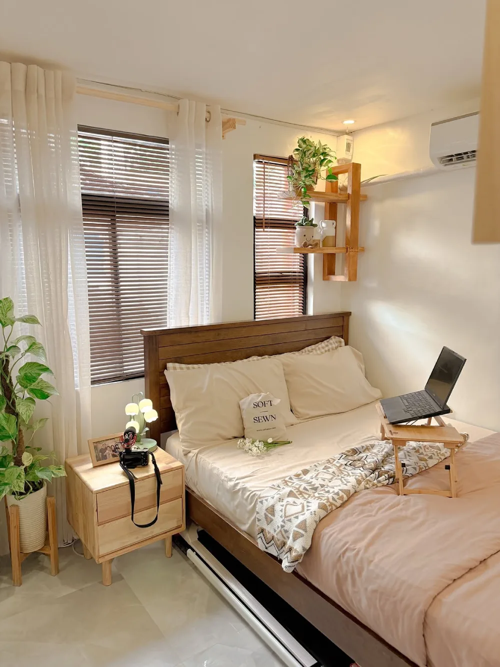 Small bedroom with a wooden bed, bedside table, wall shelf, and laptop tray