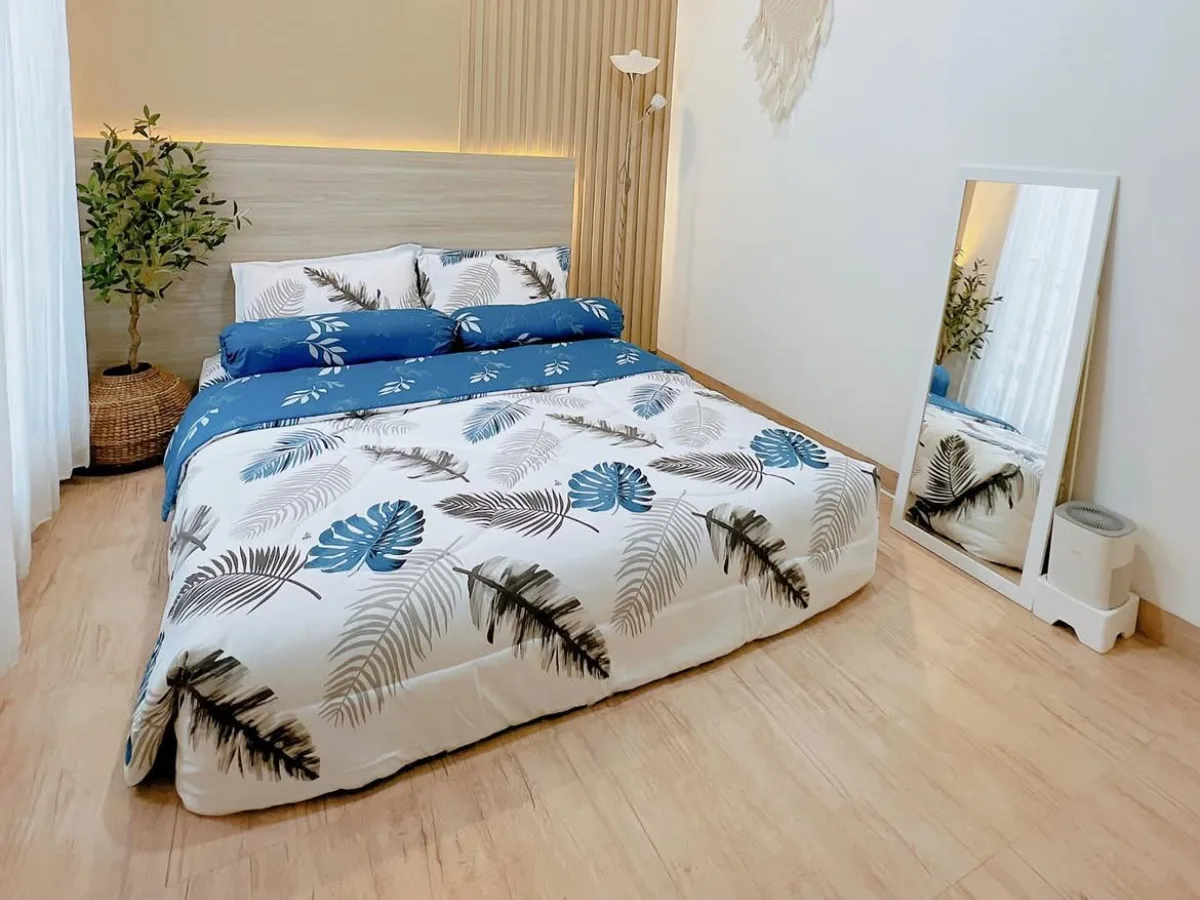 Small bedroom with a low-profile bed, wood accent wall, wall mirror, floor lamp, and minimal decor that maximizes the available space.