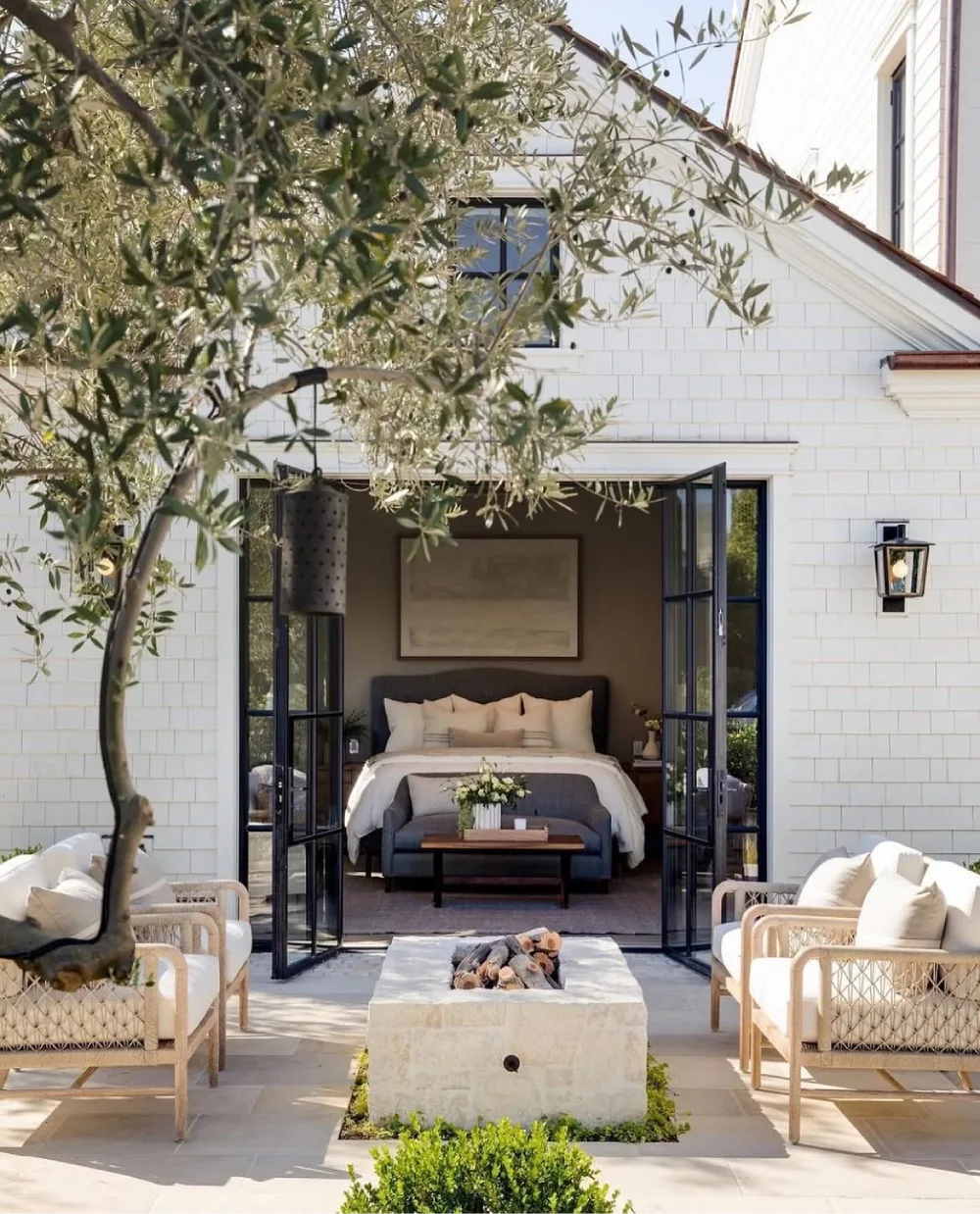bedroom opening onto an outdoor seating area through black framed doors