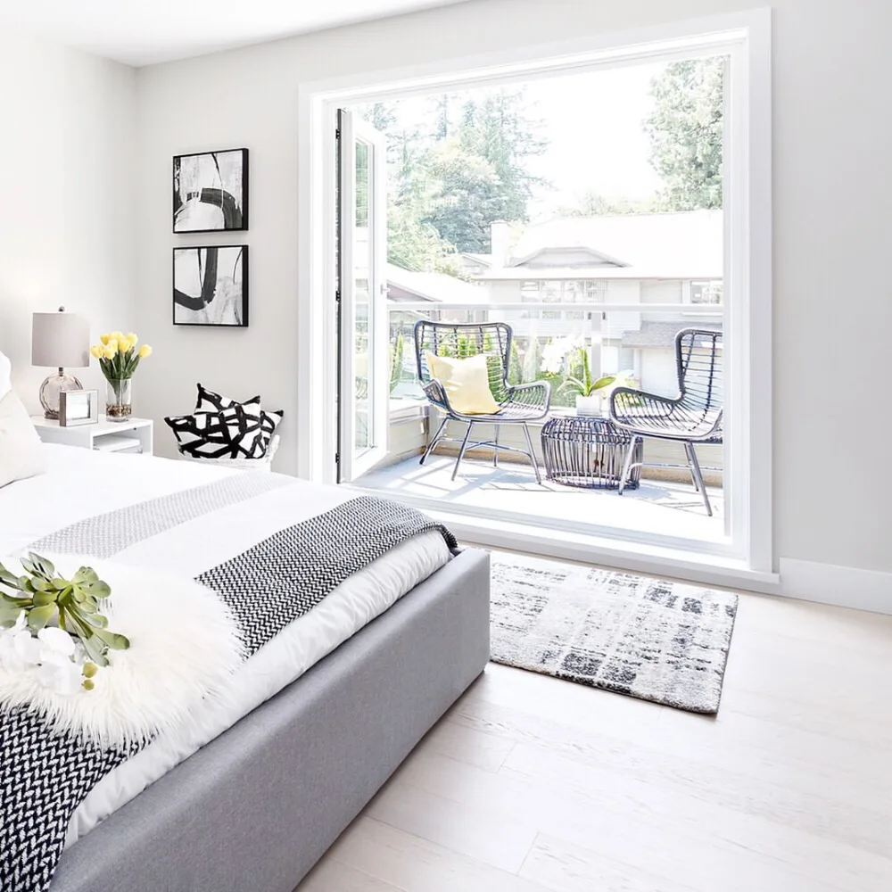 bright bedroom with a large window opening onto a furnished balcony