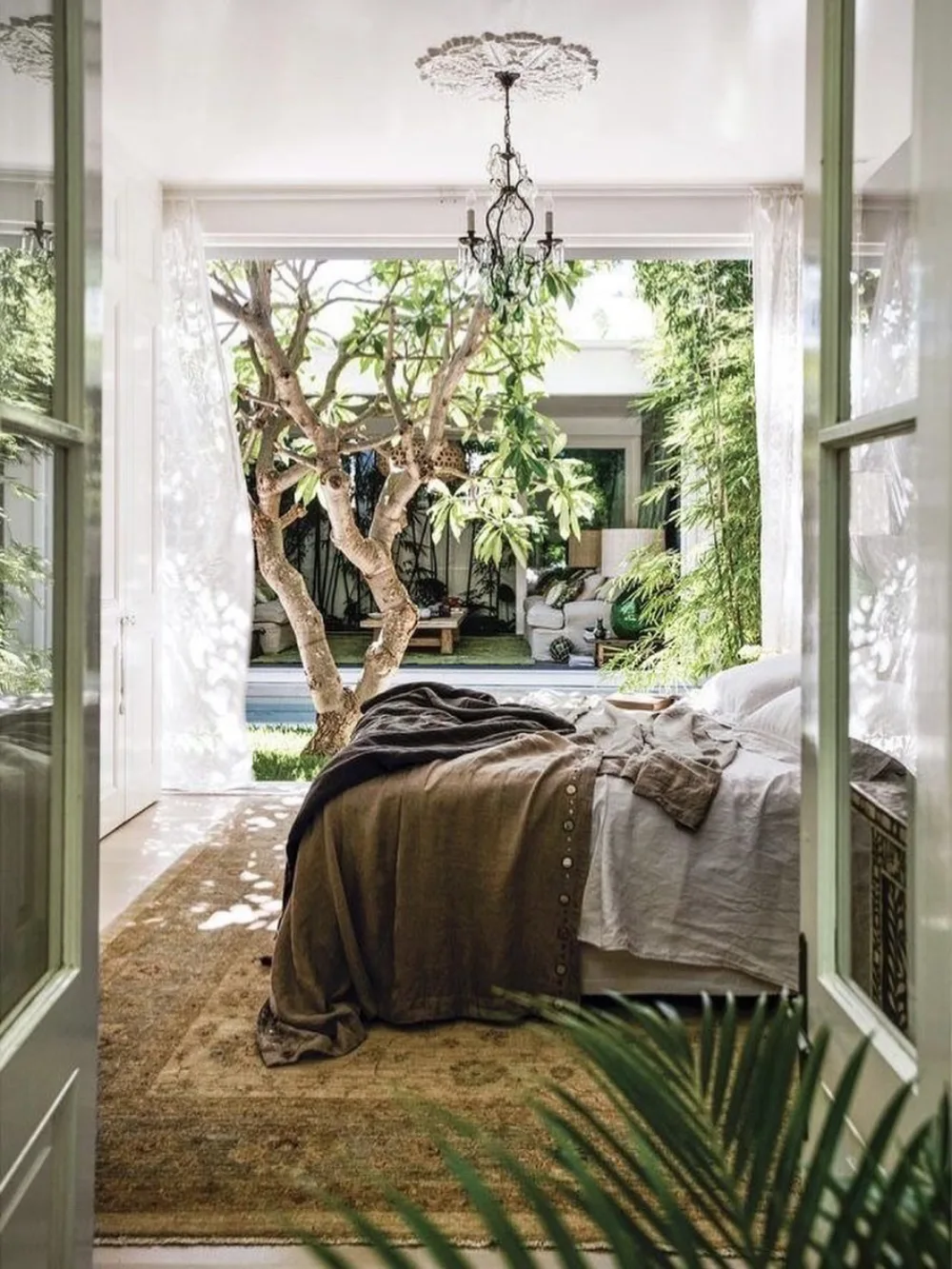 bedroom framed by open double doors with a leafy garden view