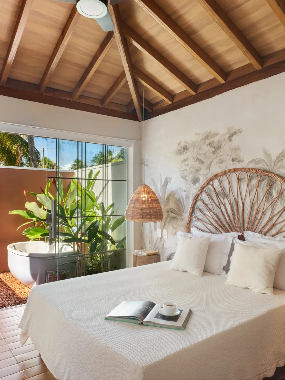 tropical bedroom with a glass-enclosed bathtub beside the bed