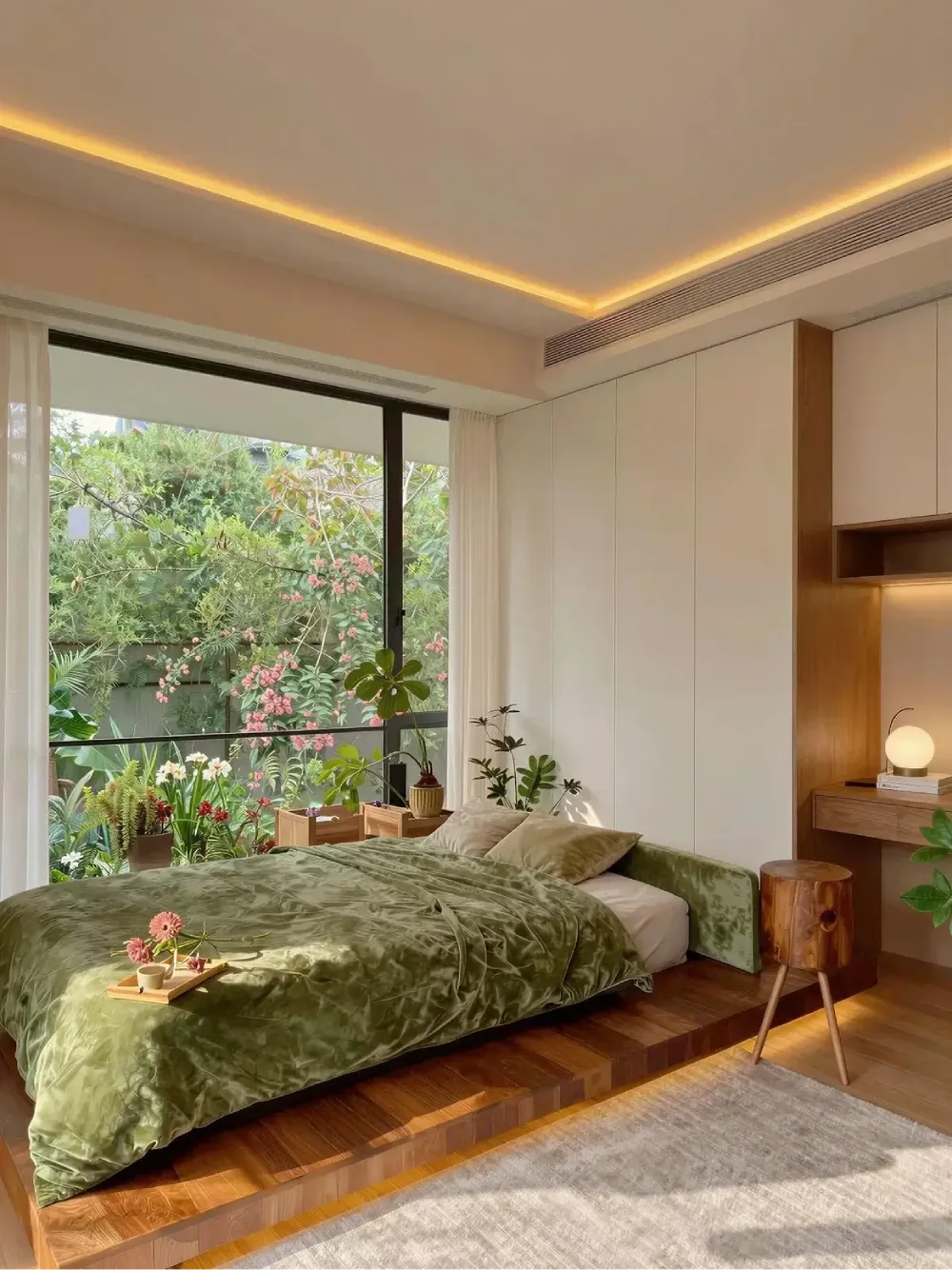 modern bedroom with green bedding, built-in white storage, and garden views