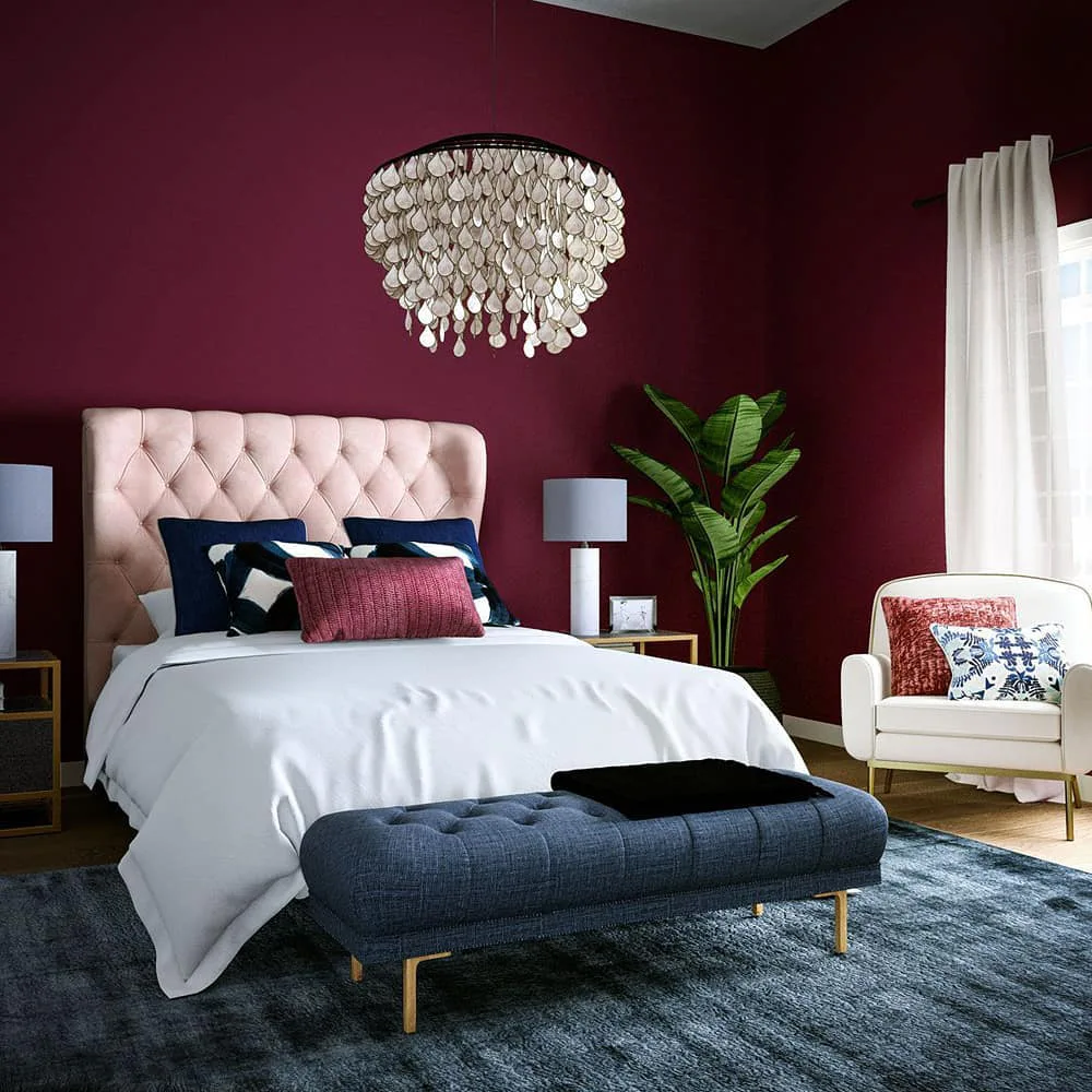 Burgundy bedroom with a blush pink tufted headboard, crisp white bedding, navy blue pillows, and a matching upholstered bench