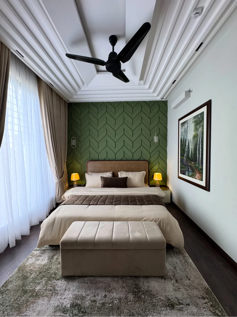 Bedroom with a dark green geometric accent wall, beige bedding, and warm bedside lighting