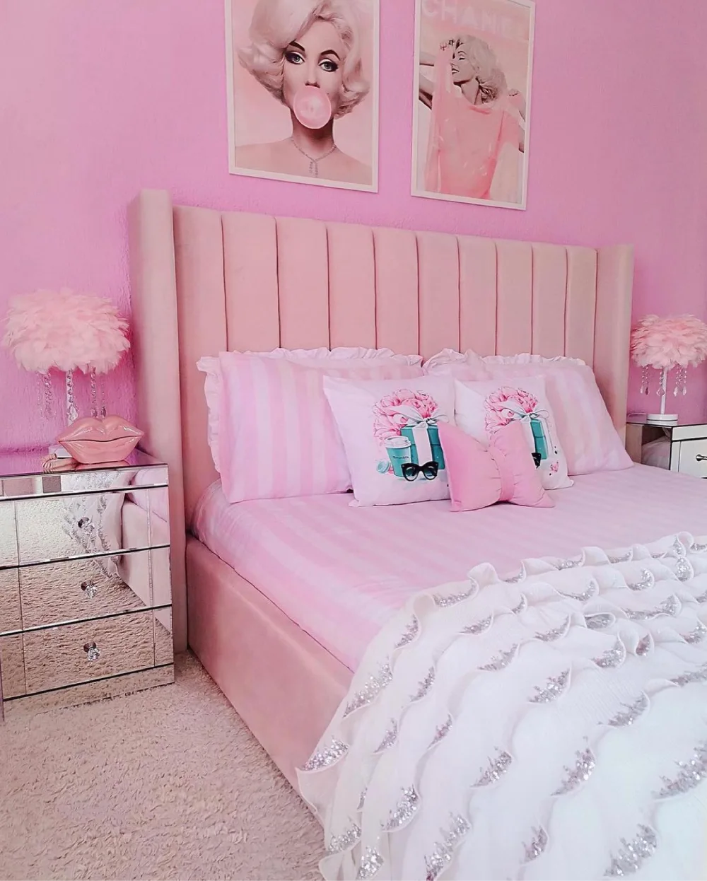 Barbie-inspired pink bedroom with a tall upholstered headboard, mirrored nightstands, and glamorous wall art