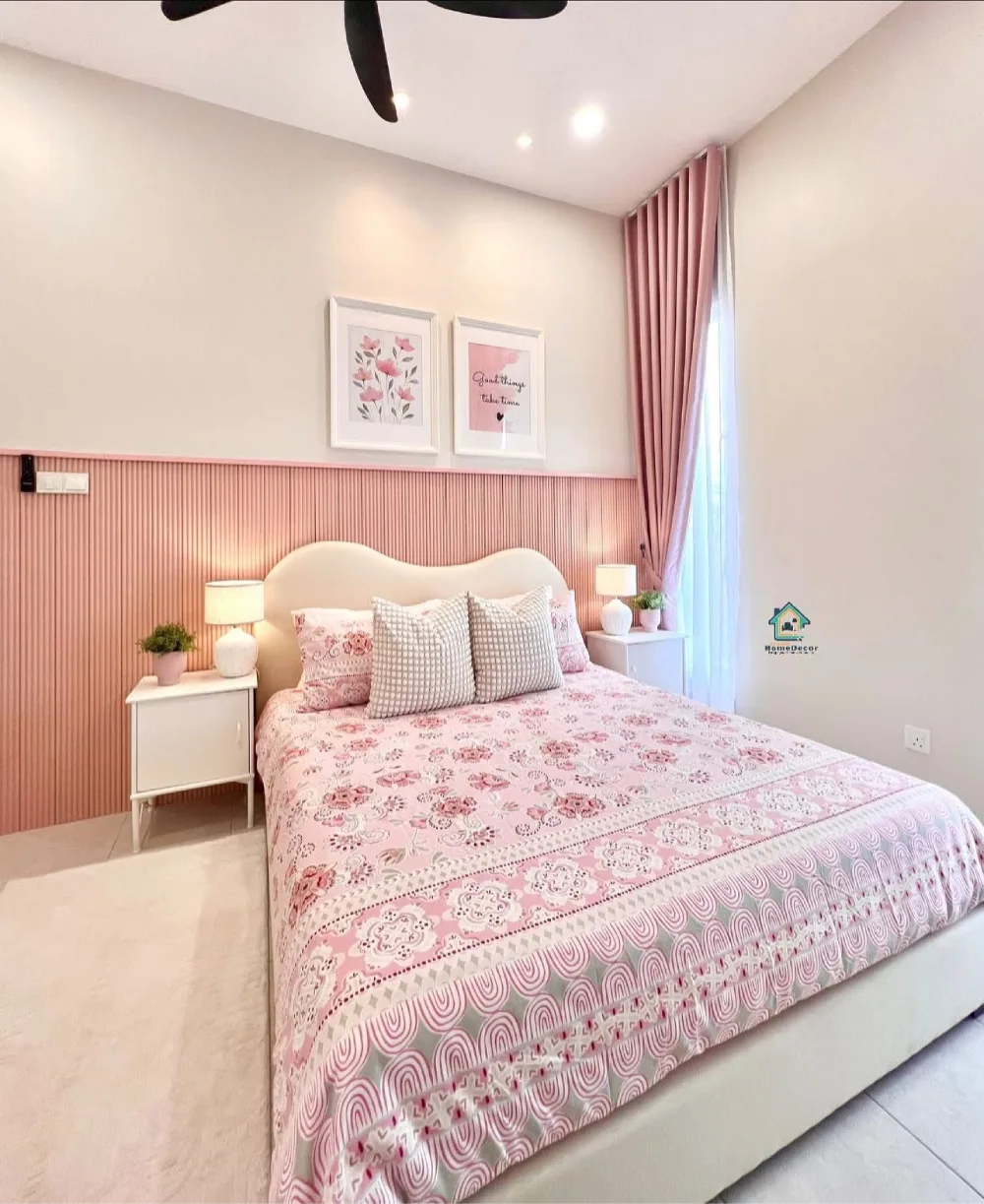 Pink bedroom with a vertical striped accent wall, white curved headboard, floral bedding, and matching blush curtains