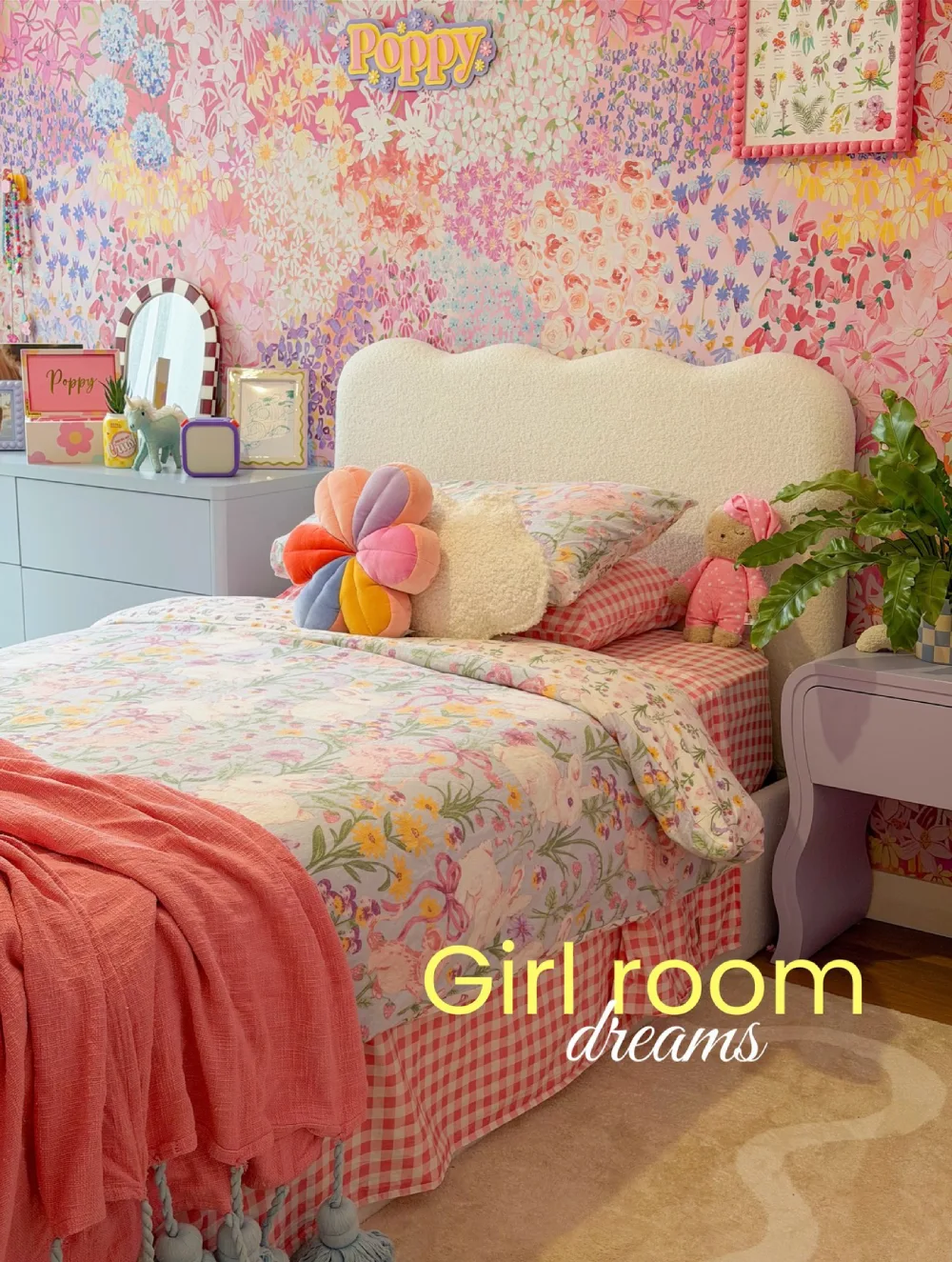 Dopamine decor bedroom with colorful floral wallpaper, a cream upholstered headboard, pastel flower pillow, pink bedding, and playful decorative accents
