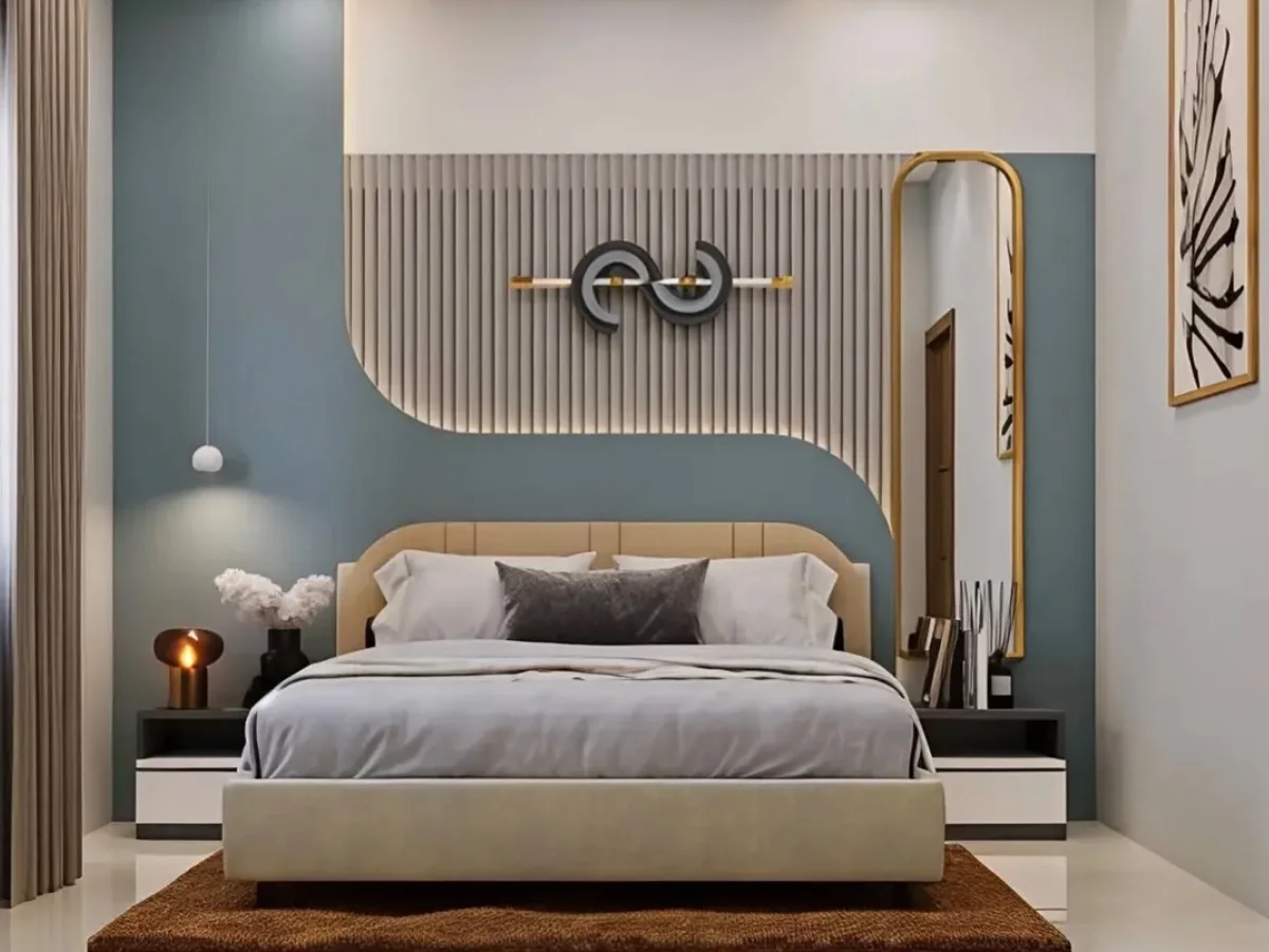 Modern bedroom featuring a teal accent wall, curved beige upholstered bed, vertical wood slat headboard, warm LED ceiling lighting, and minimalist decor.