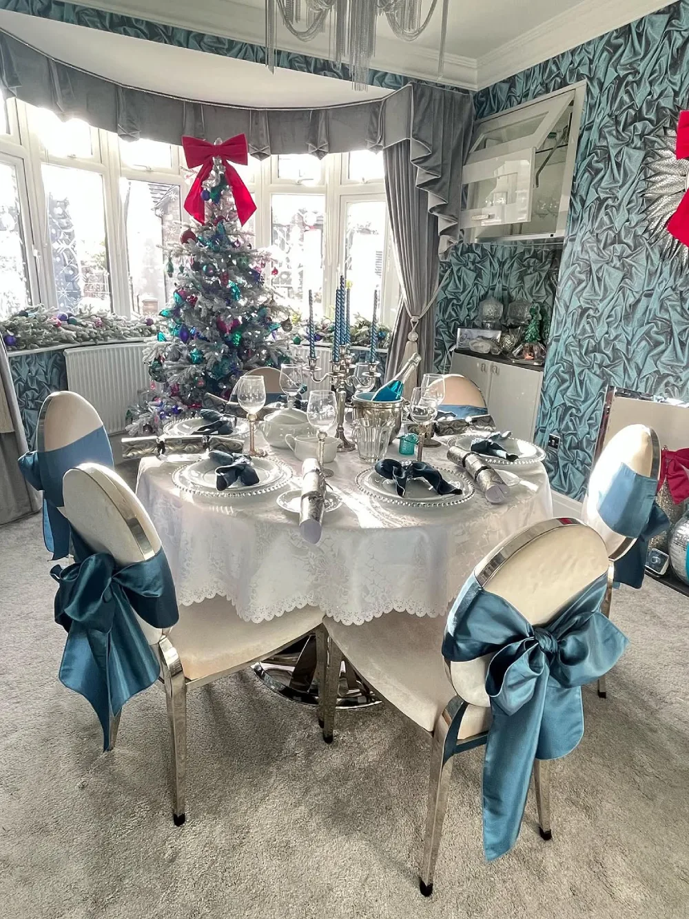 Elegant winter dining room with blue accents, white table linens, and a decorated Christmas tree