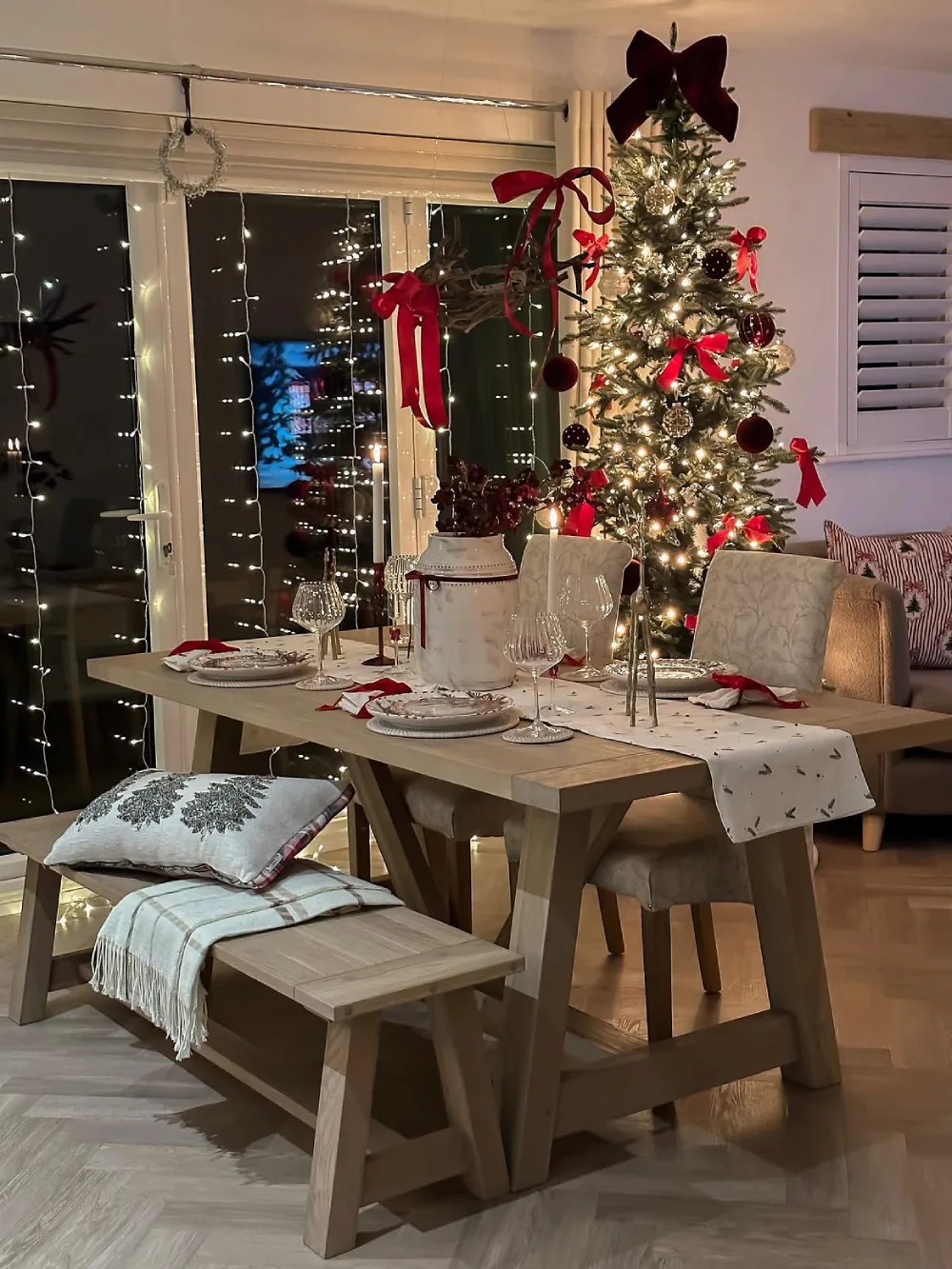 Winter dining room glowing with Christmas lights, red ribbons, and a decorated Christmas tree