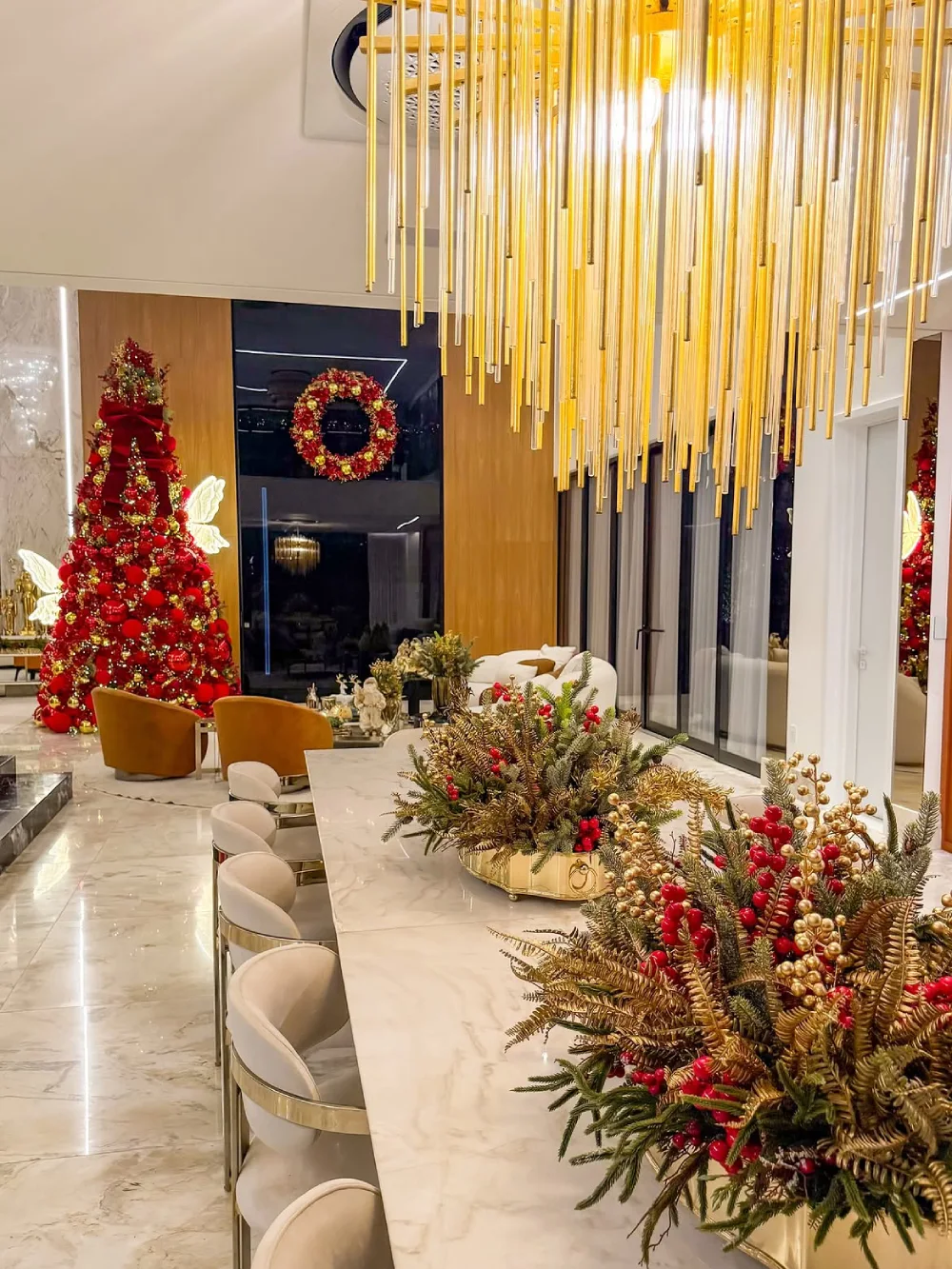 Elegant modern dining room with a long marble table, festive greenery, red berries, and gold accents