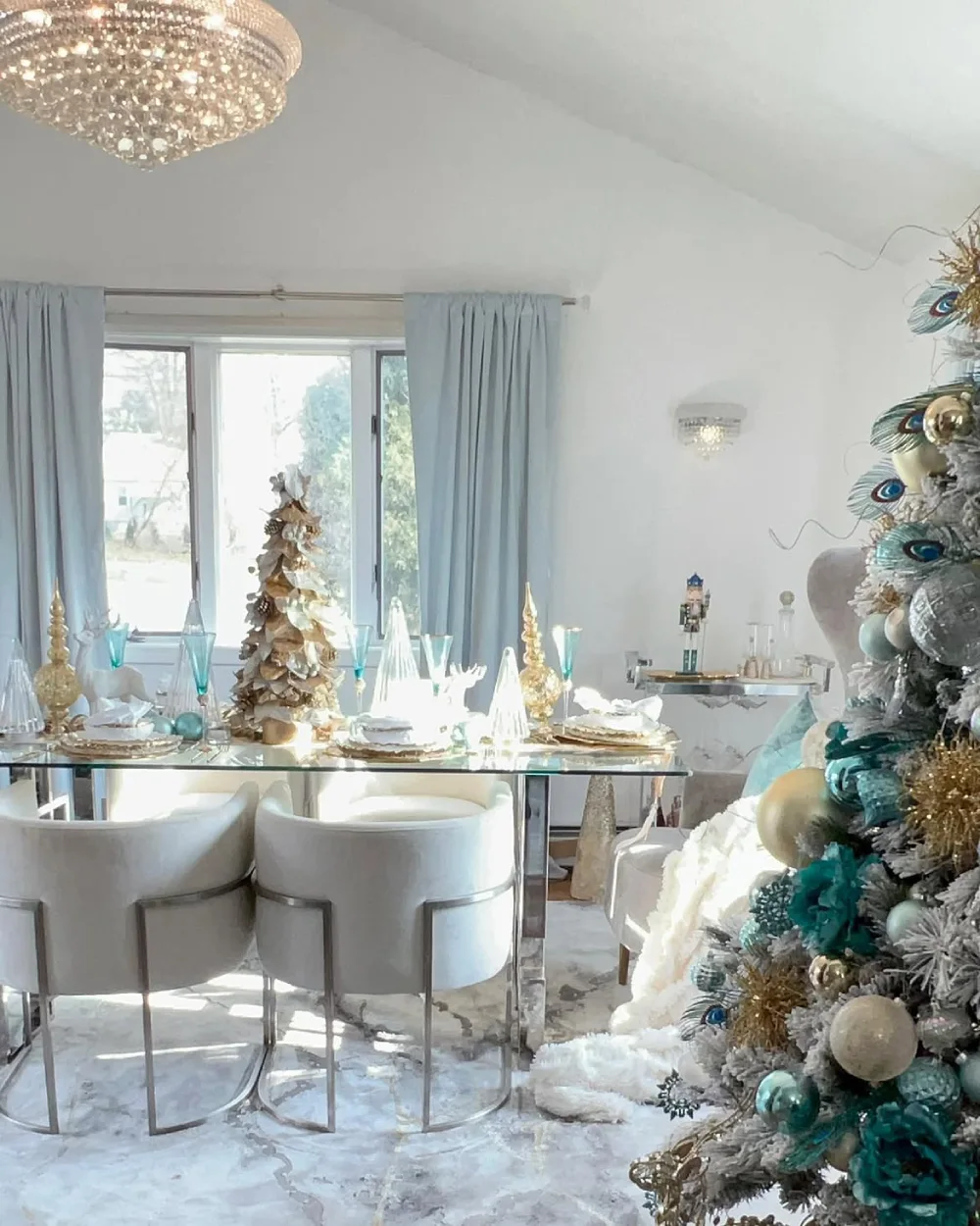 Elegant white winter dining room with silver and turquoise Christmas decorations and a glass dining table