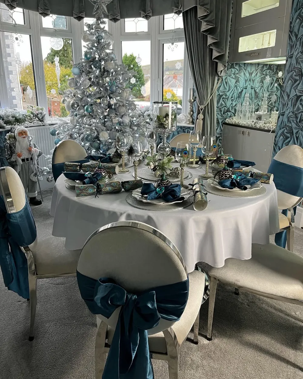 Elegant winter dining room with a silver Christmas tree, blue accents, and a formal table setting