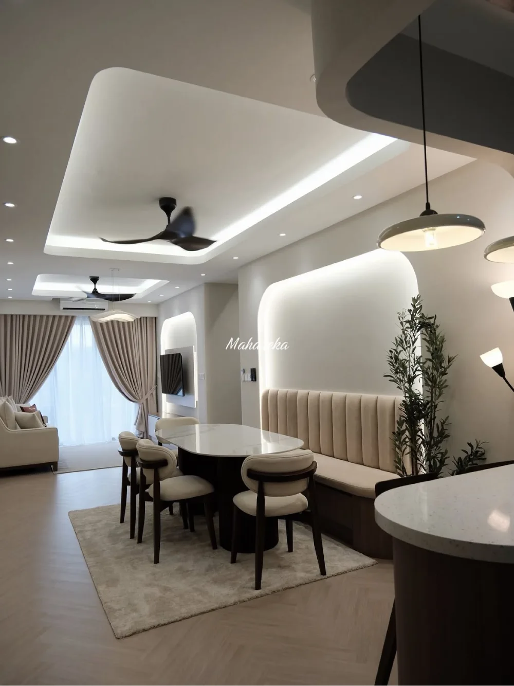 Elegant open dining area with a built-in upholstered bench, round table, pendant lights, and nearby kitchen island