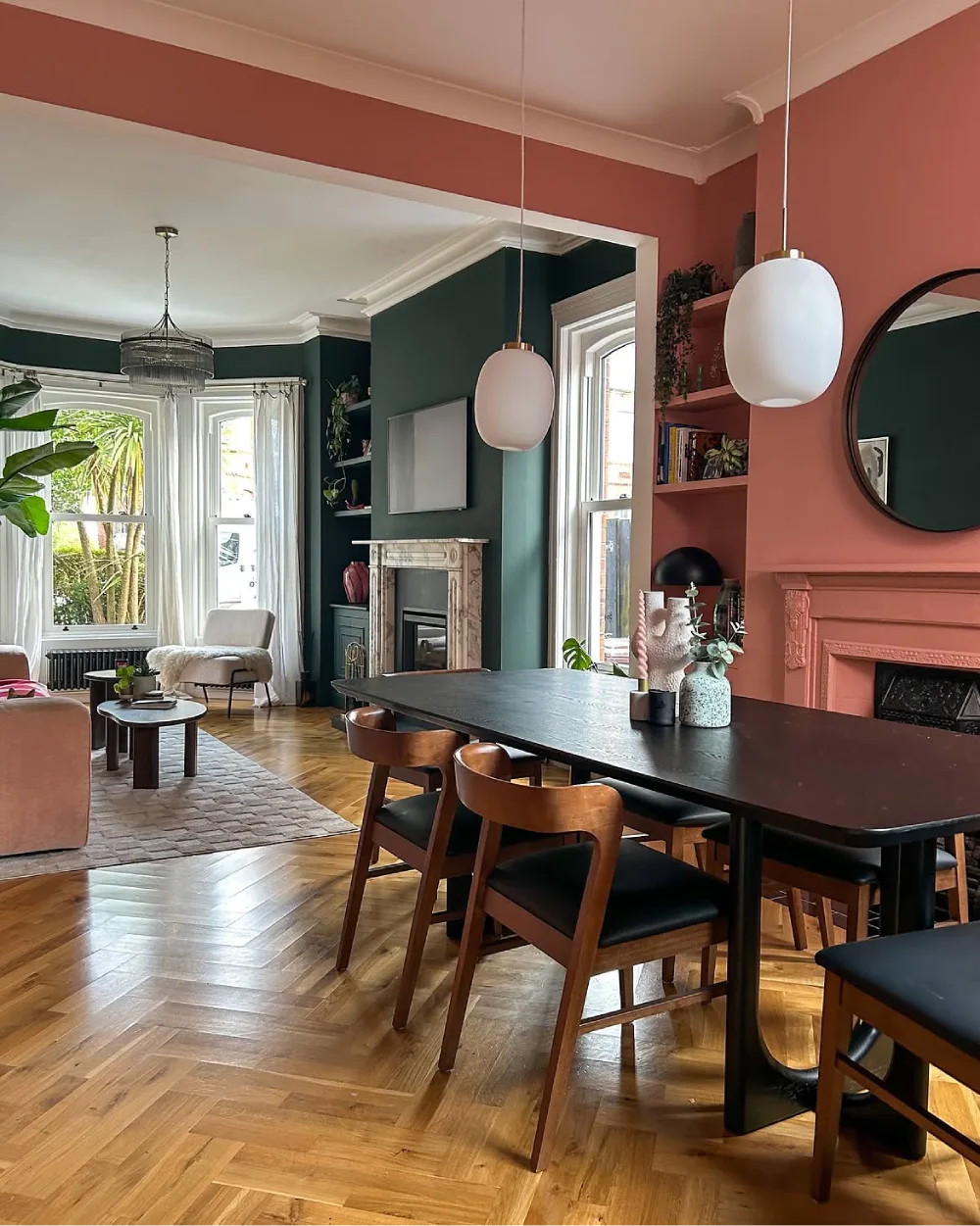 Open dining room with a dark wood table, black chairs, colorful walls, and an adjoining living room