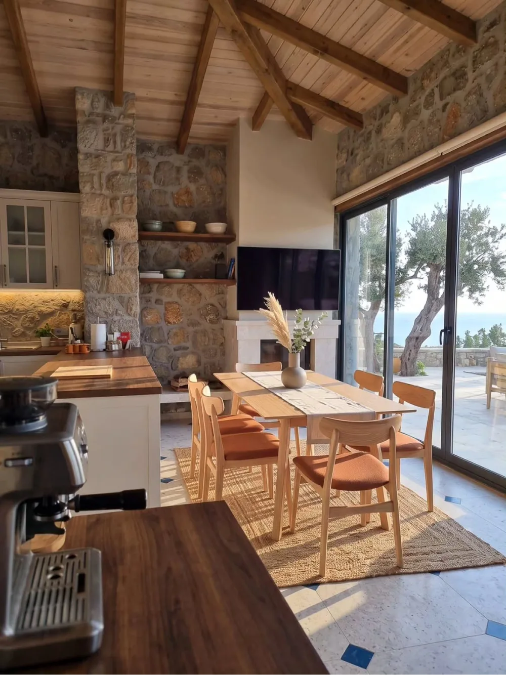 Open dining area beside a kitchen with a wood table, upholstered chairs, and warm built-in cabinetry