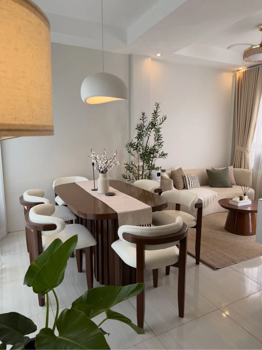 Open dining and living room with a rounded wood table, upholstered chairs, and a comfortable sofa