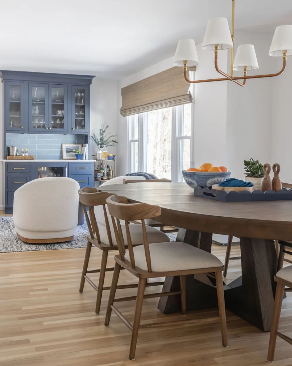Dining room with a large wood table, upholstered chairs, blue kitchen cabinets, and a brass chandelier