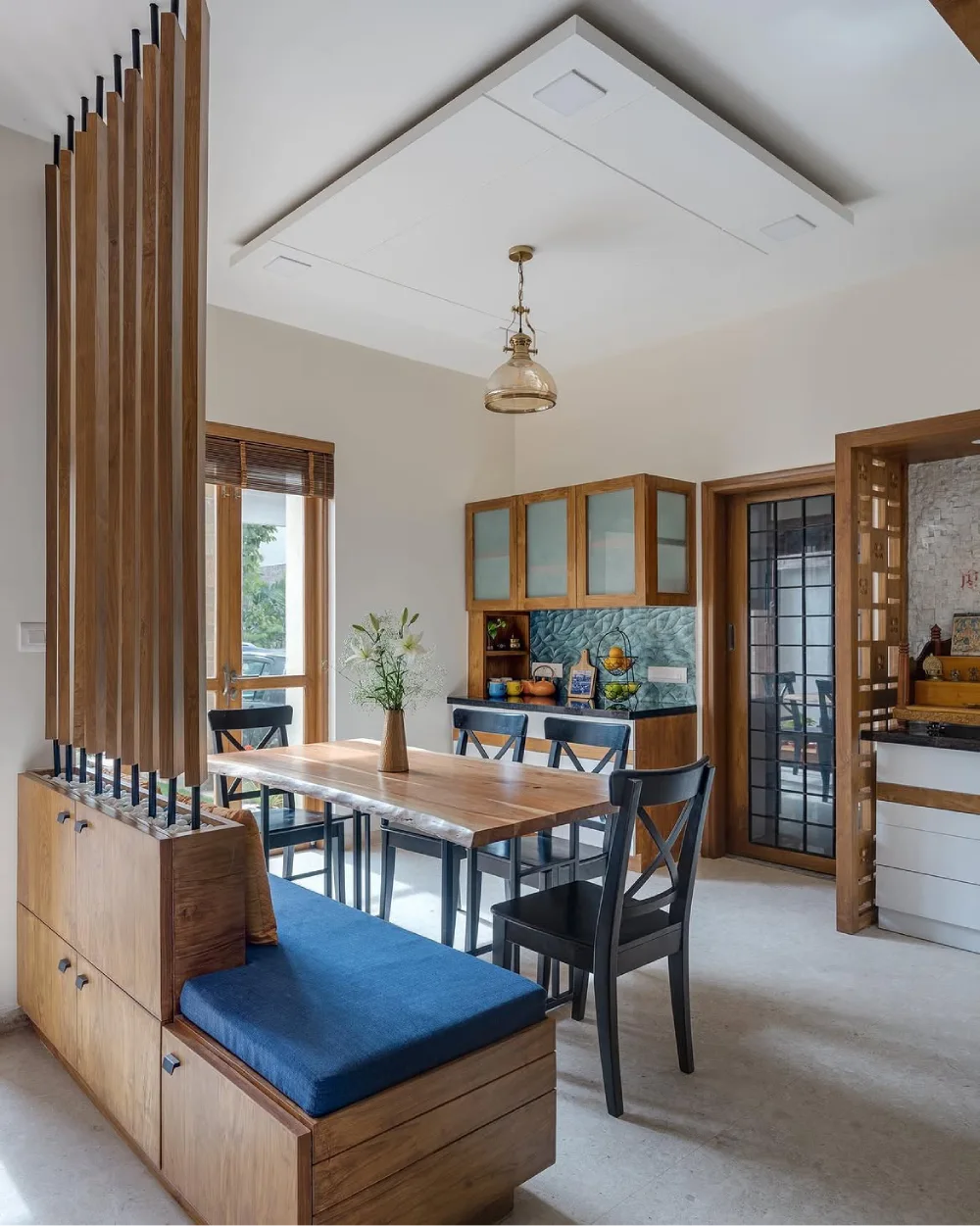 Bright dining room with a large rustic wood table, black chairs, and expansive garden-facing windows