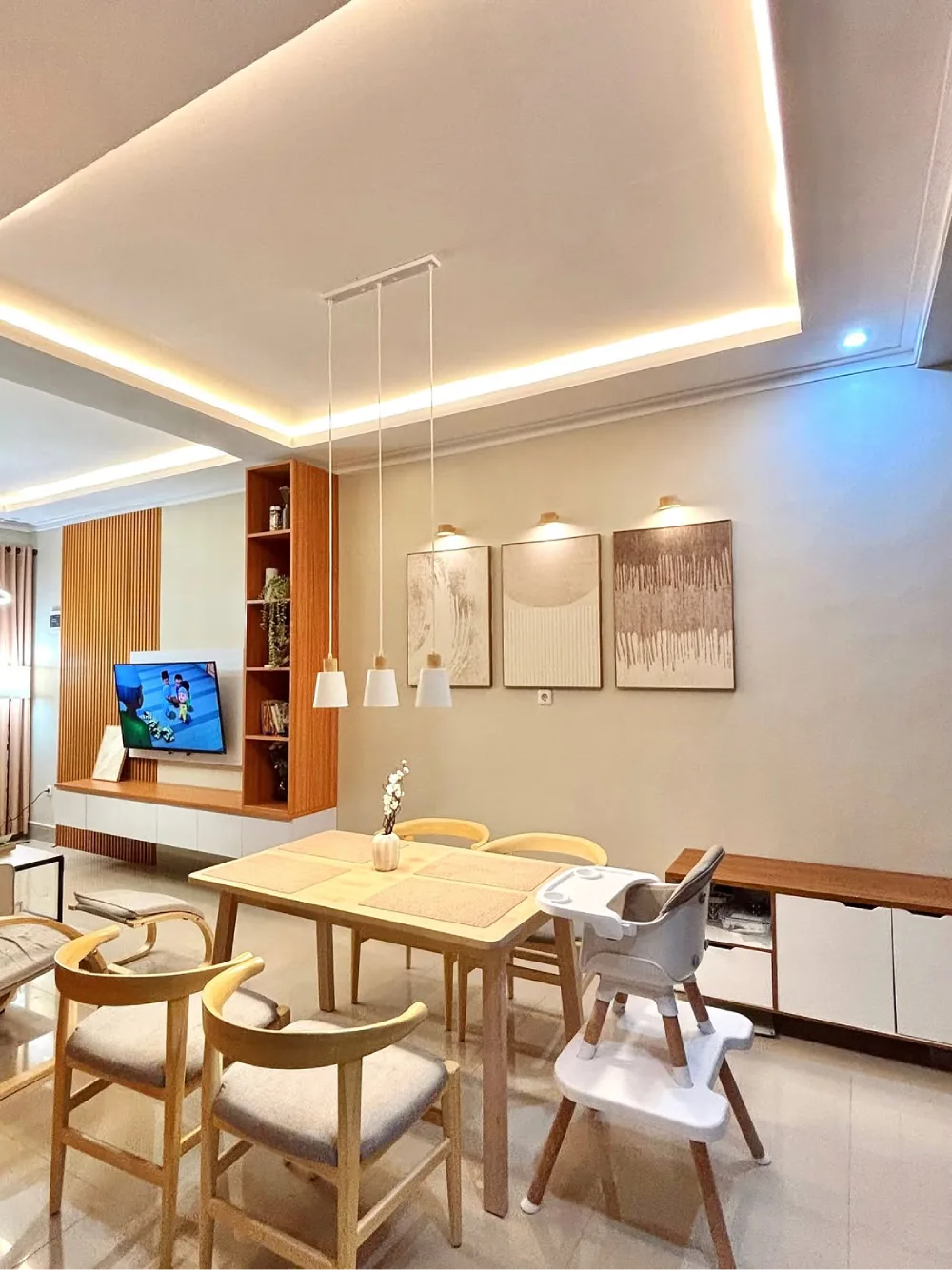 Family-friendly open dining area with a wood table, pendant lights, built-in storage, and adjacent living room
