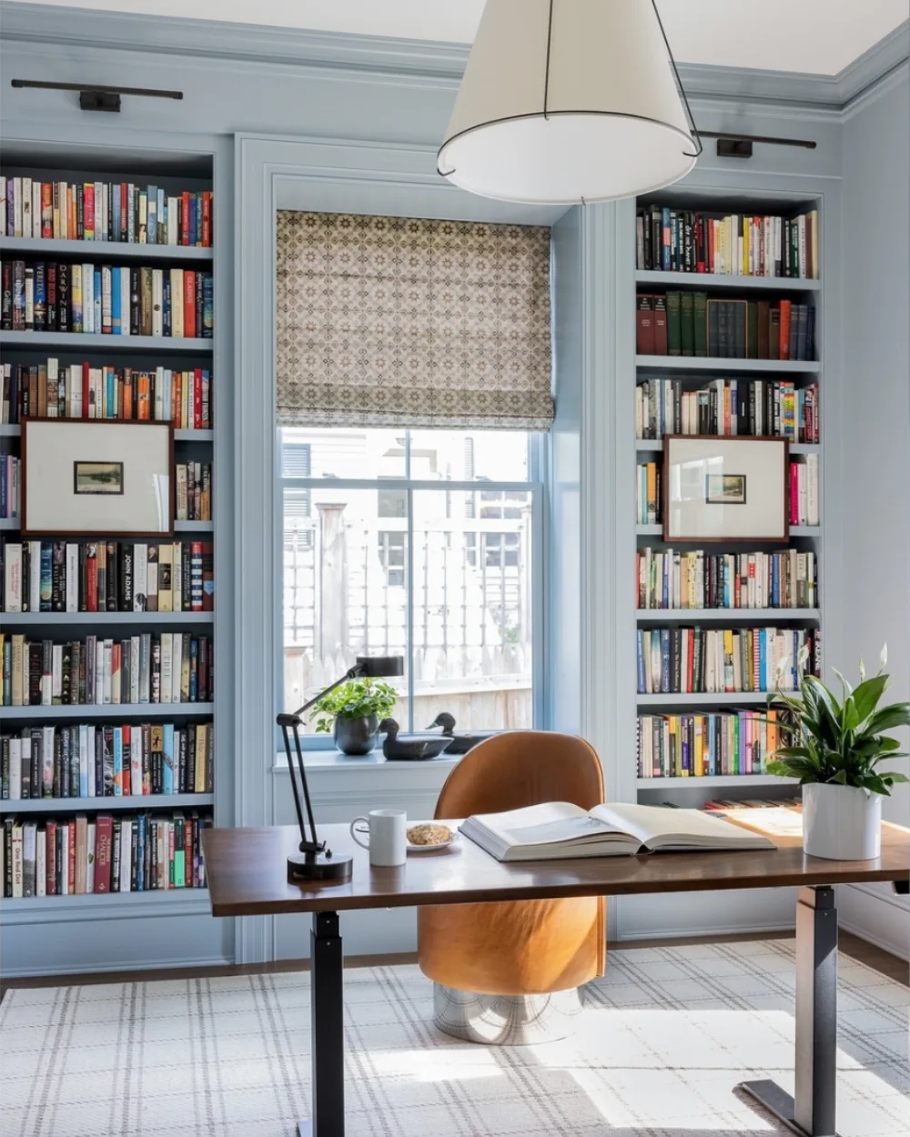 blue home office with symmetrical bookshelves surrounding a window
