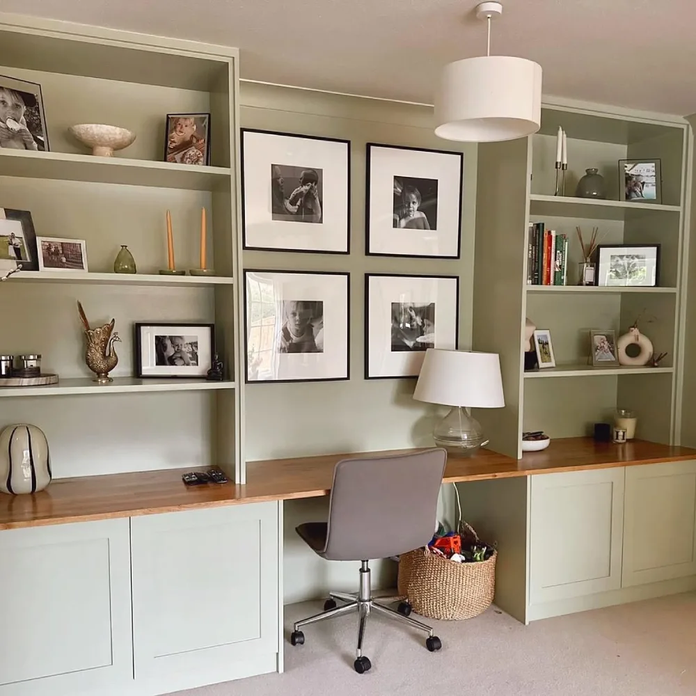 soft green built-in bookshelf with books, decor, and a home office desk